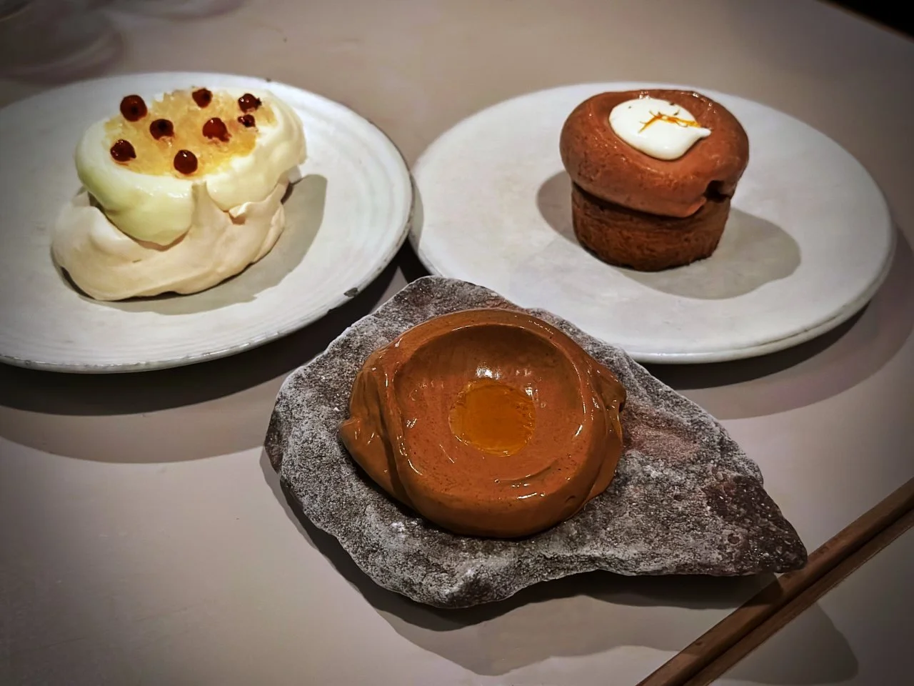 Drei verschiedene Nachspeisen auf hellen Tellern und einem Stein im Berliner Restaurant Otto. Die Auswahl zeigt Vadims Fokus auf das Produkt und die visuelle Gestaltung der regionalen Küche.