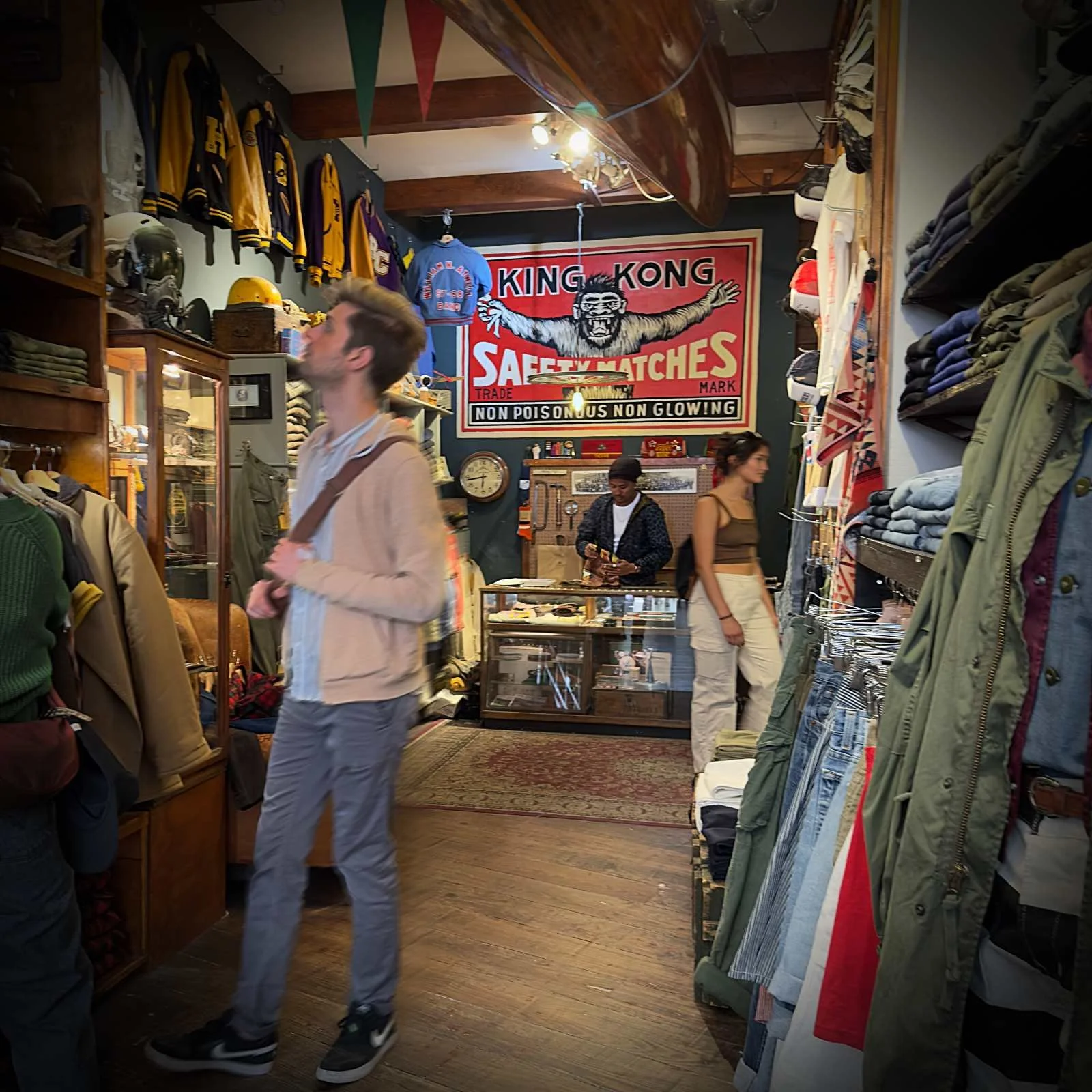 Blick in den Laden Concrete Matter: An der Rückwand hängt ein großes King-Kong-Plakat. Kunden stehen zwischen Regalen voller Jeans und Vintage-Kleidung.