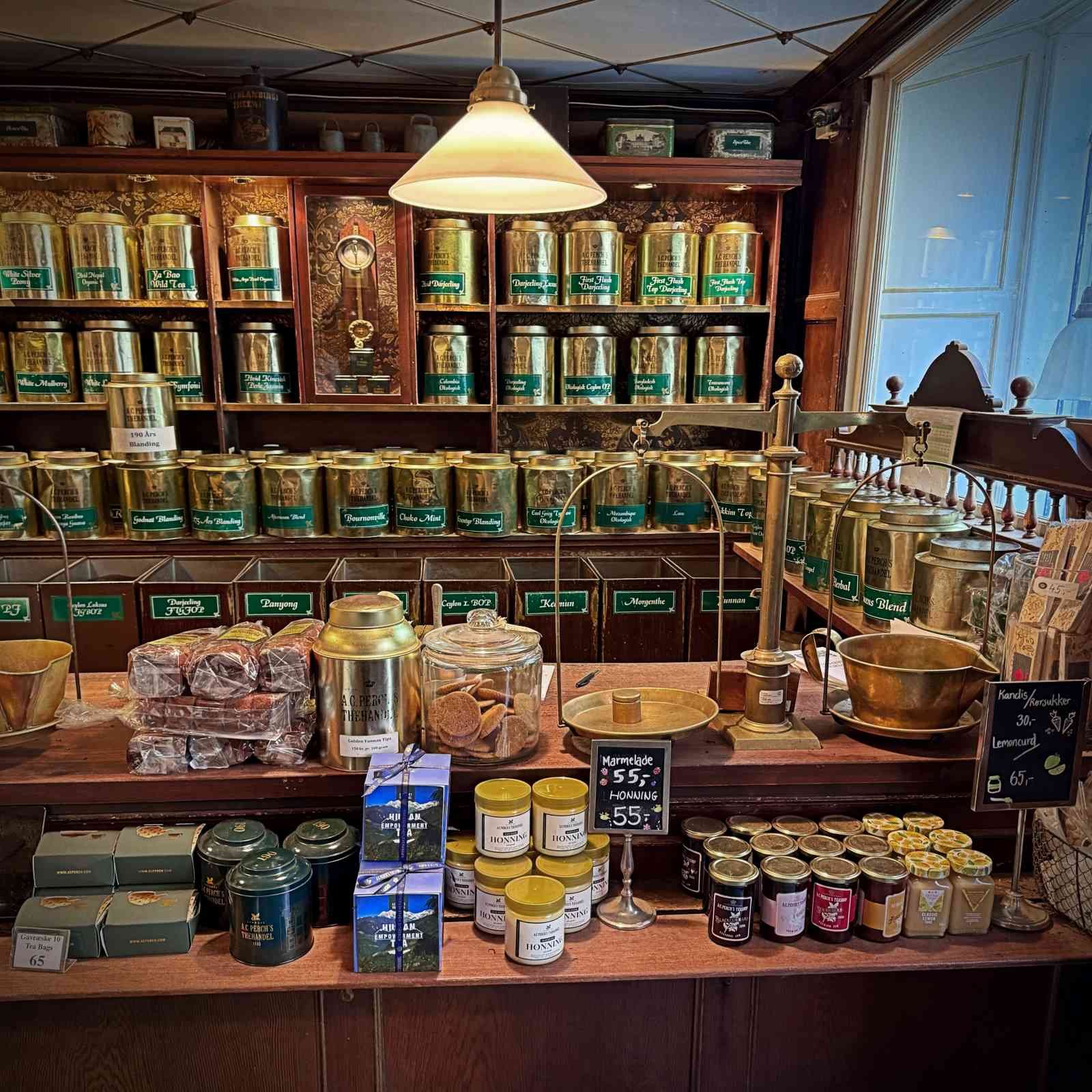 Ein Holzregal im Teegeschäft A.C. Perch's Thehandel, in dem verpackte Teegeschenke, Pappschachteln und Teelichte einsortiert sind.
