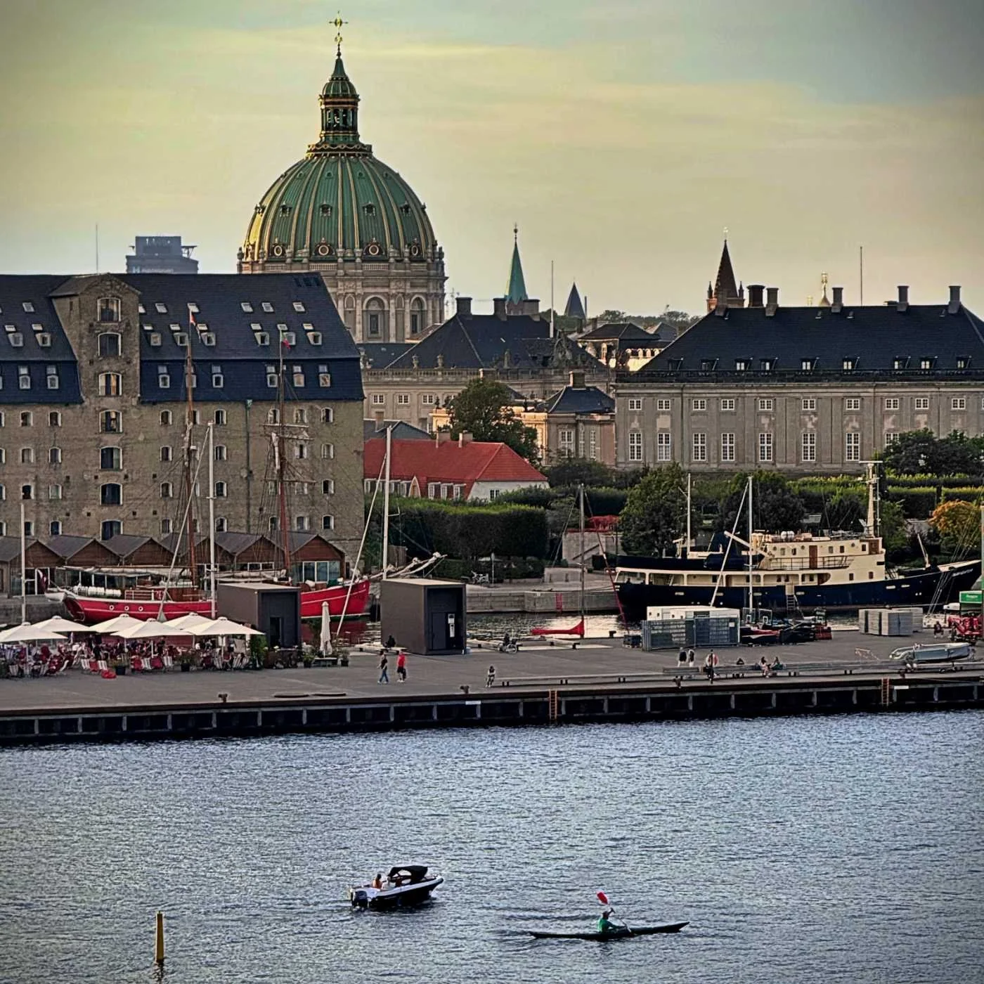 Blick vom 25 Hours Hotel Paper Island auf den Kopenhagener Hafen mit einem Kajakfahrer, Booten und der Kuppel der Frederikskirche.