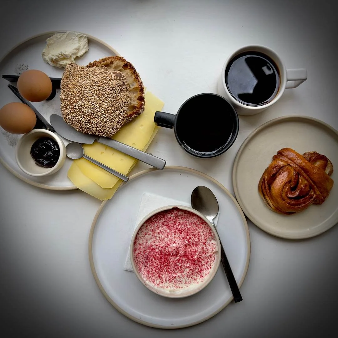 Frühstück im Café Apotek 57 in Kopenhagen mit gekochten Eiern, Käse, Brot, schwarzem Kaffee, einer Zimtschnecke und einem Dessert.