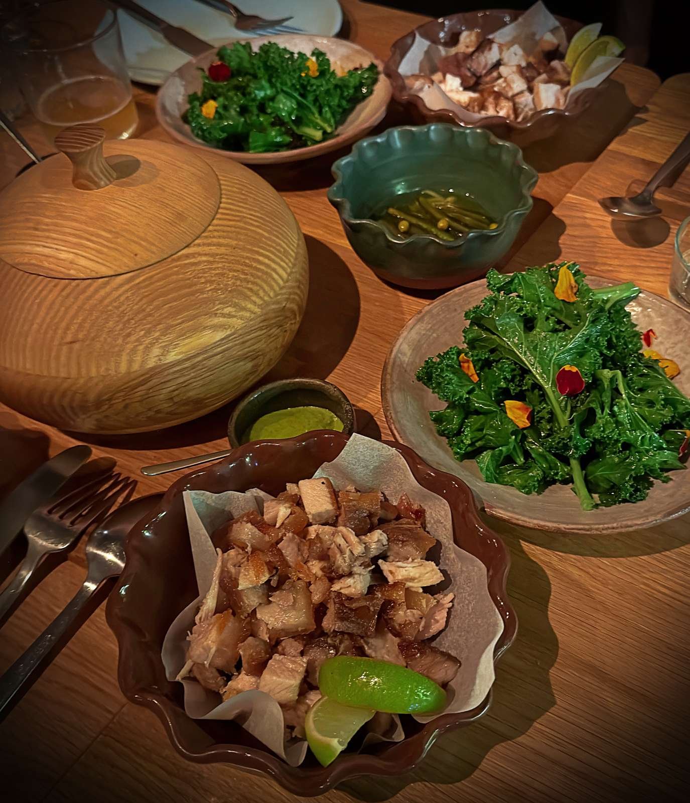 Tacos de Carnitas mit Schweinefleisch, Limetten und Grünkohlsalat auf einem Holztisch im Restaurant Sanchez in Kopenhagen Vesterbro.
