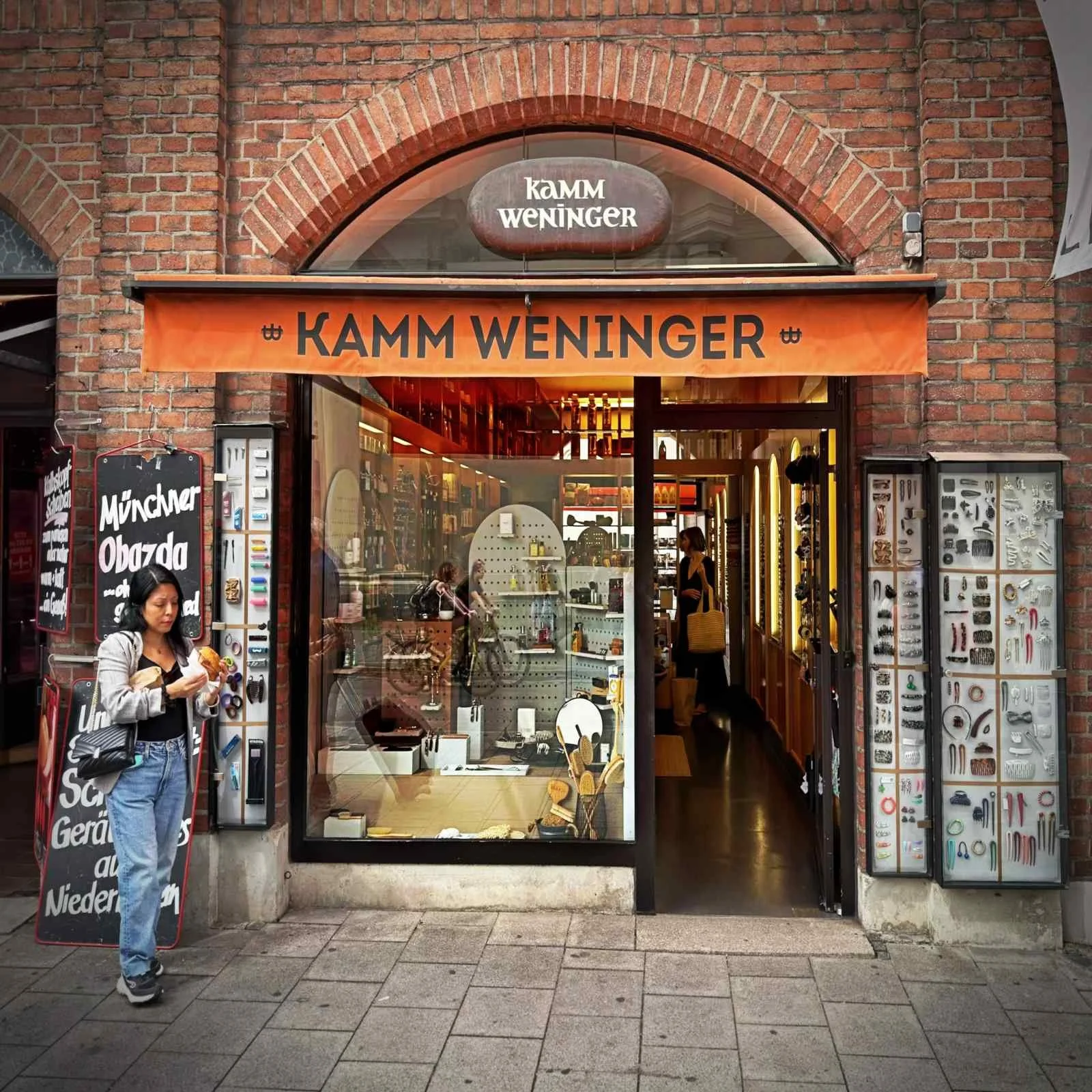 Fassade des Traditionsgeschäfts Kamm Weninger im Backsteinbau mit Schaukästen voller Bürsten, Kämme und Haar-Accessoires.