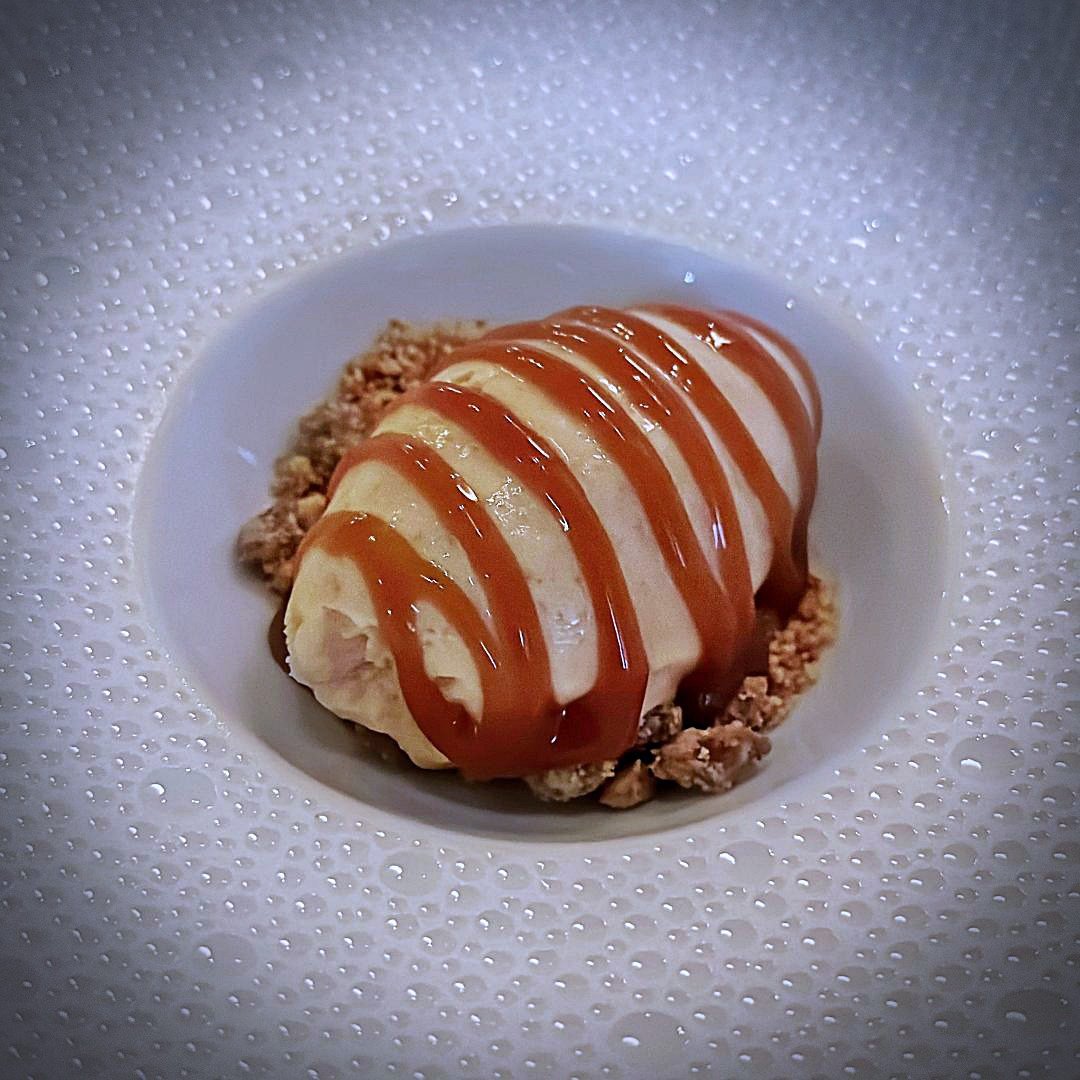 Eiscreme-Dessert auf Bröseln mit spiralförmig aufgetragener Karamellsauce, serviert im Restaurant JA in Amsterdam.