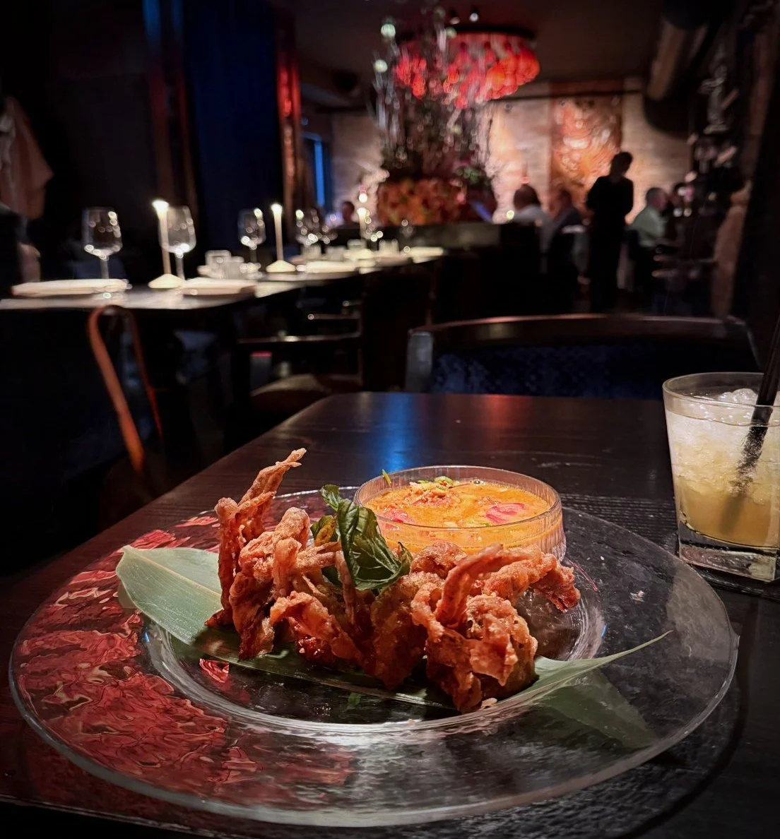 Servierte Vorspeise auf Glasplatte mit frittierten Softshell-Crabs und Dip in einem stilvoll gedeckten Restaurant mit gedämpftem Licht.