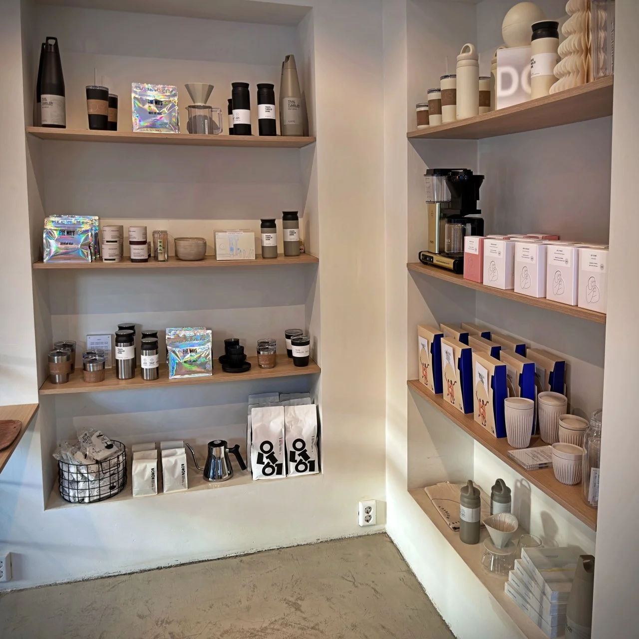 Shelves inside The Coffee District on Willemsparkweg in Amsterdam, filled with coffee beans, cups, and brewing gear – from filters to thermos mugs.
