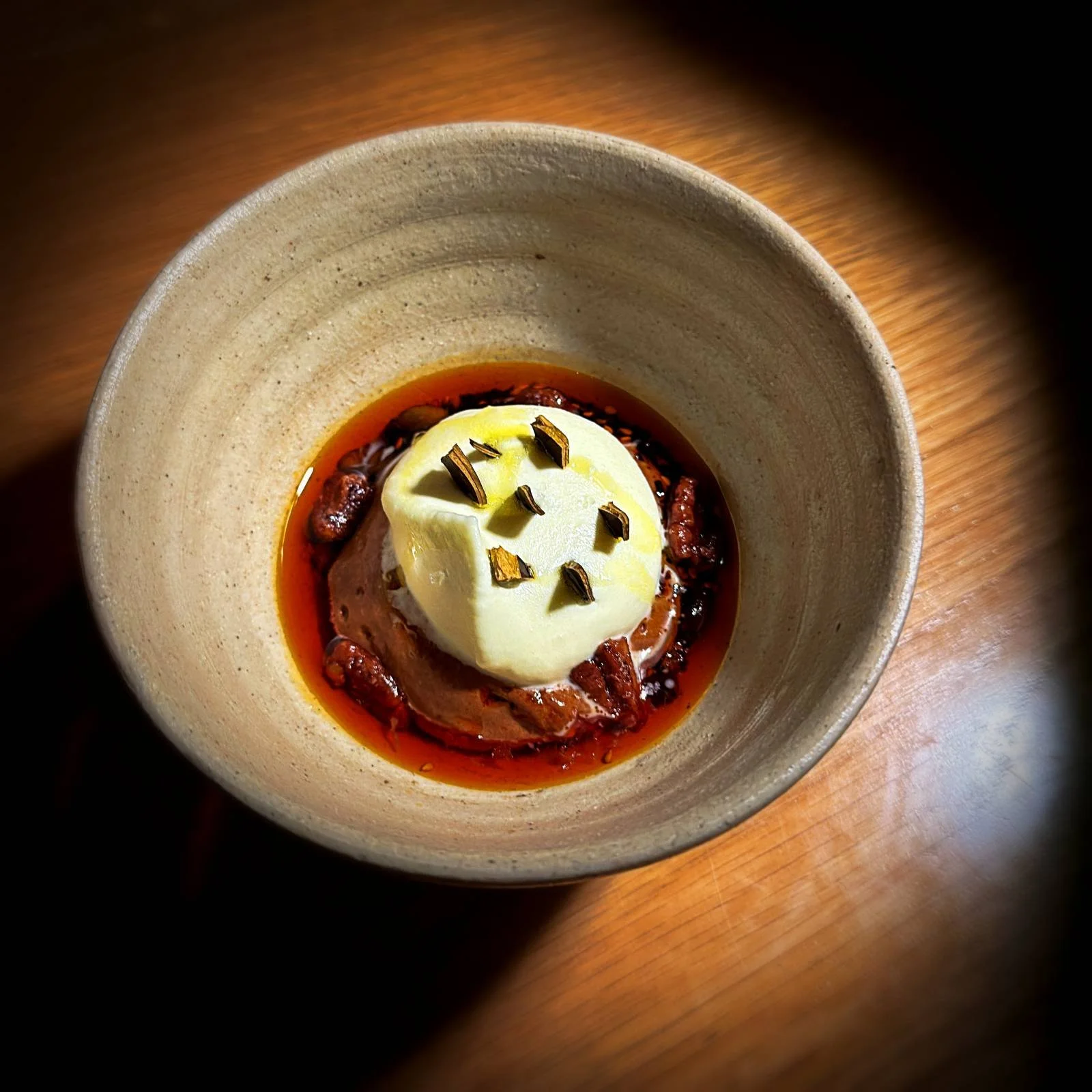 Schokoladenmousse mit weißer Haube und Pekannüssen serviert in einer Tonschale im Restaurant Sanchez in Kopenhagen Vesterbro.