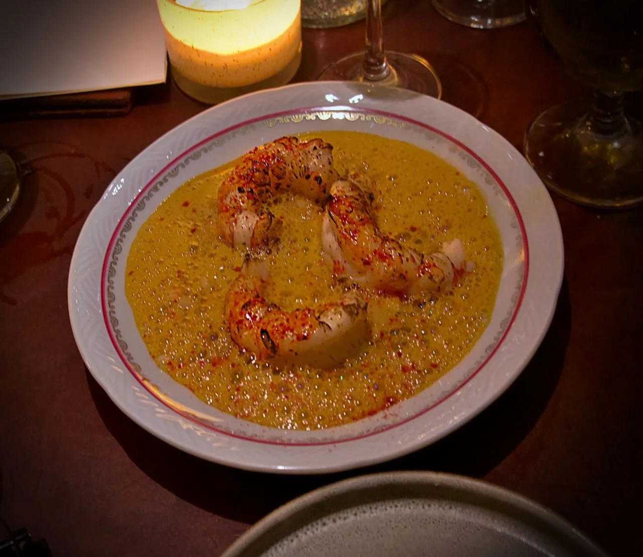 Das Foto zeigt eine Portion norwegischen Hummer (Kaisergranat) in einer schaumigen, gelben Sauce, die auf einem verzierten Porzellanteller im Restaurant Främmat in Stockholm serviert wird.