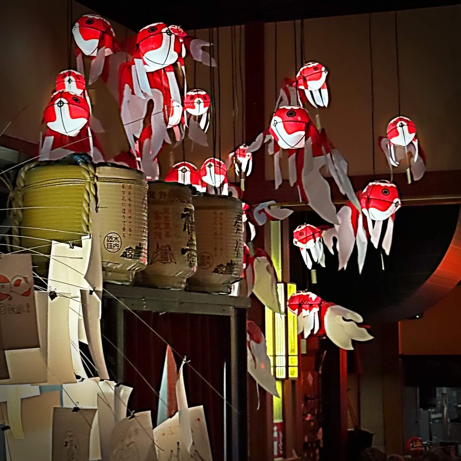 Detailed view of the bar at Miyakodori restaurant in Stockholm with red and white paper fish mobiles and traditional sake barrels.