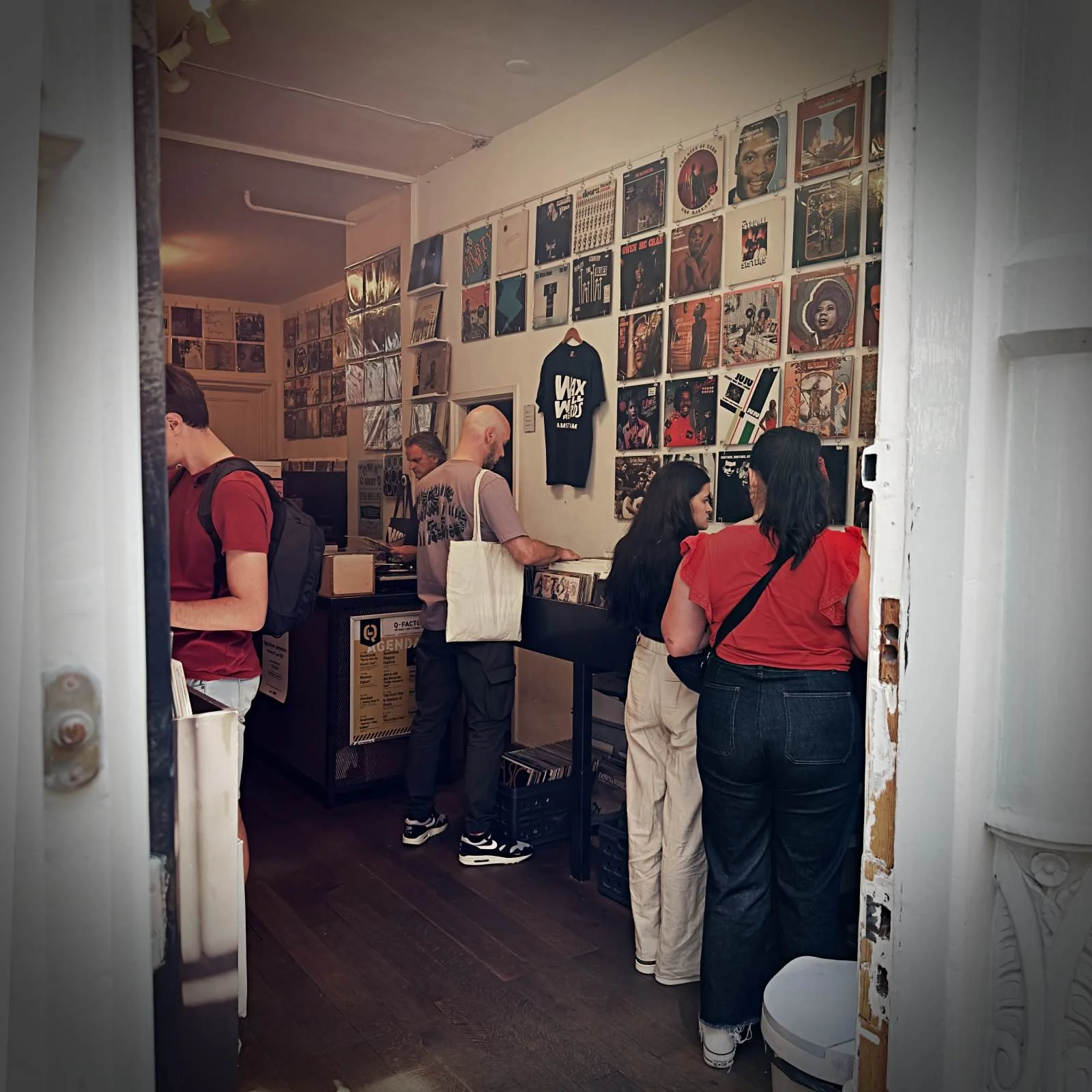 Kunden stöbern bei Wax Well Records in den Neun Straßen nach Schallplatten. An den Wänden hängen Reihen von verschiedenen Plattenhüllen.