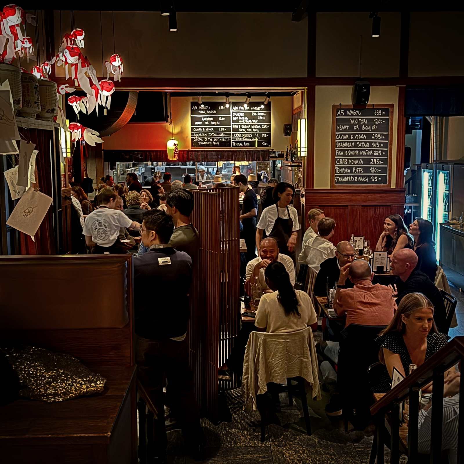 The busy dining area of Miyakodori restaurant in Stockholm with seated guests, staff, and menu boards on the walls.