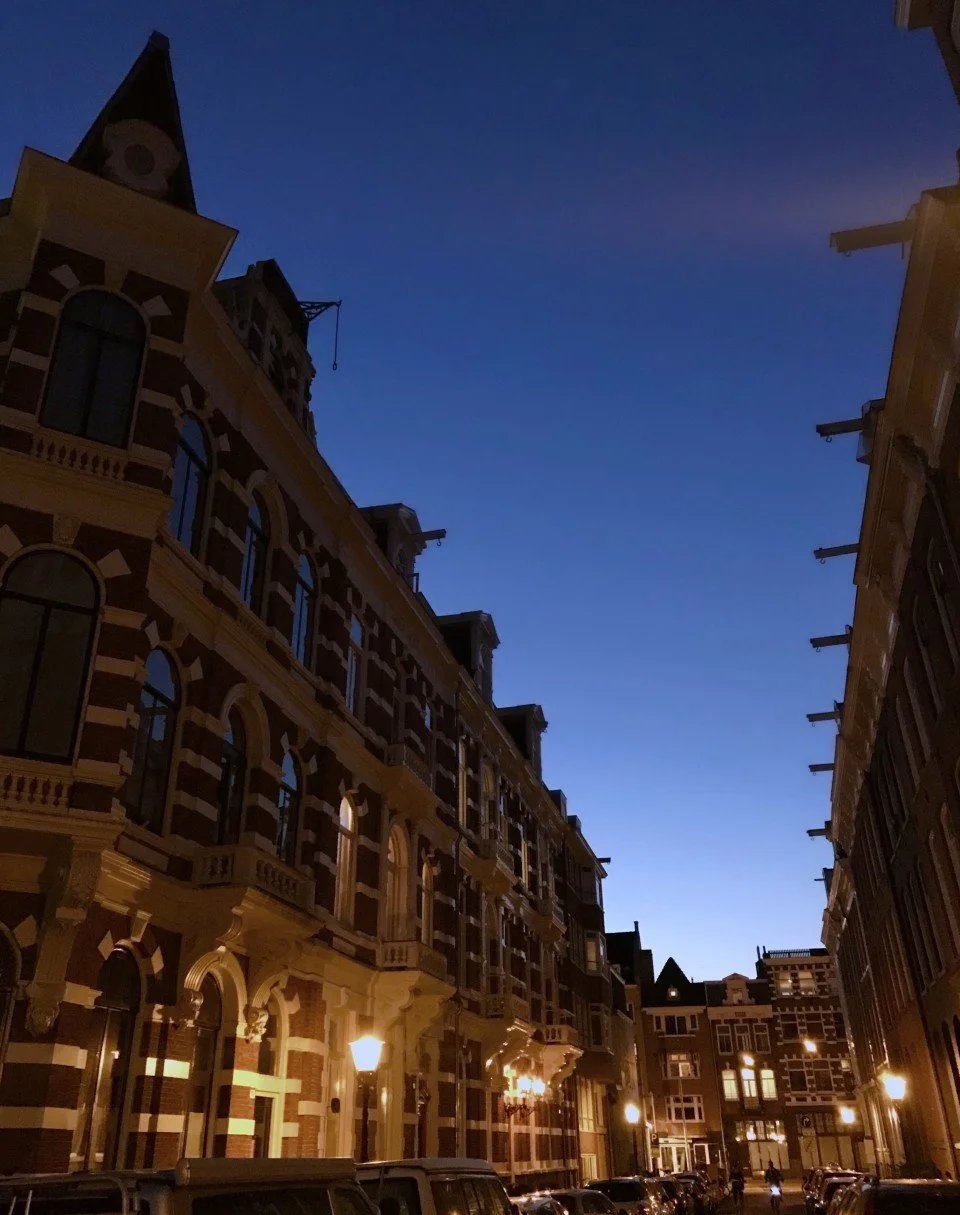 Dark blue night sky over the typical brick houses of the Helmersbuurt. Street lamps illuminate the quiet residential street in Amsterdam-West.