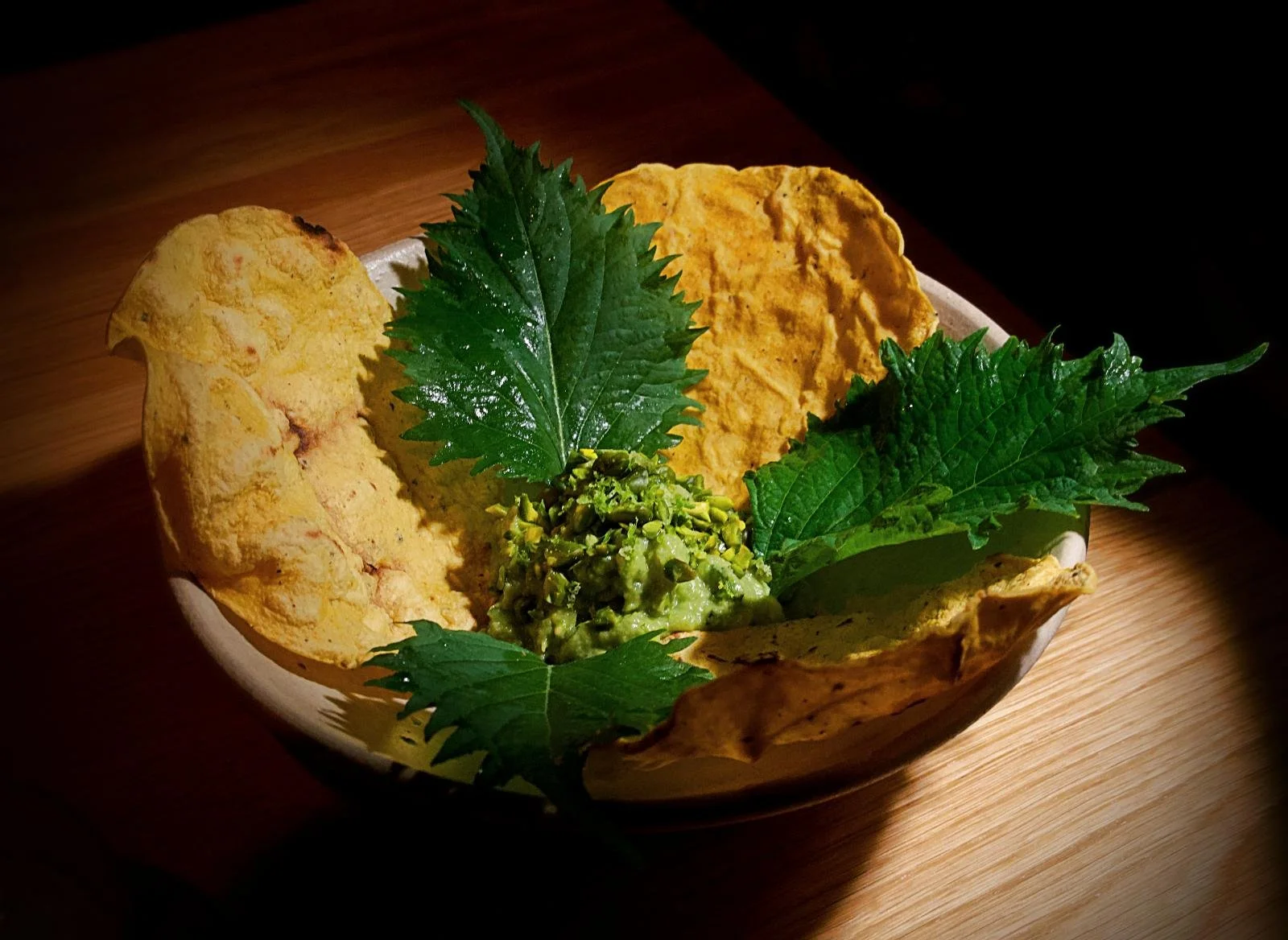 Guacamole mit Pistazien, Shiso-Blättern und Tostadas serviert in einer Schüssel im Restaurant Sanchez in Kopenhagen Vesterbro.