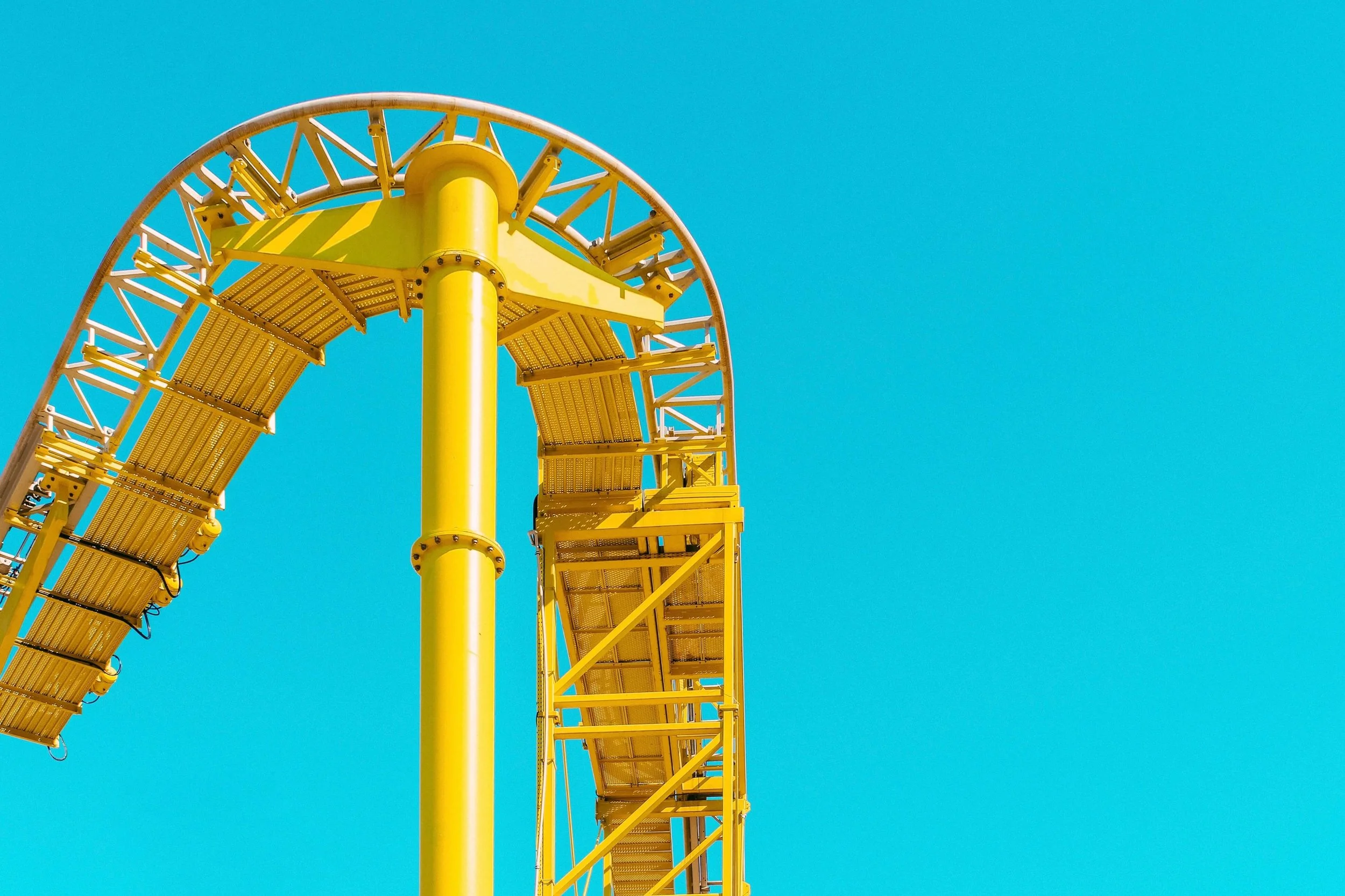 bright-yellow-rollercoaster-track-against-blue-sky