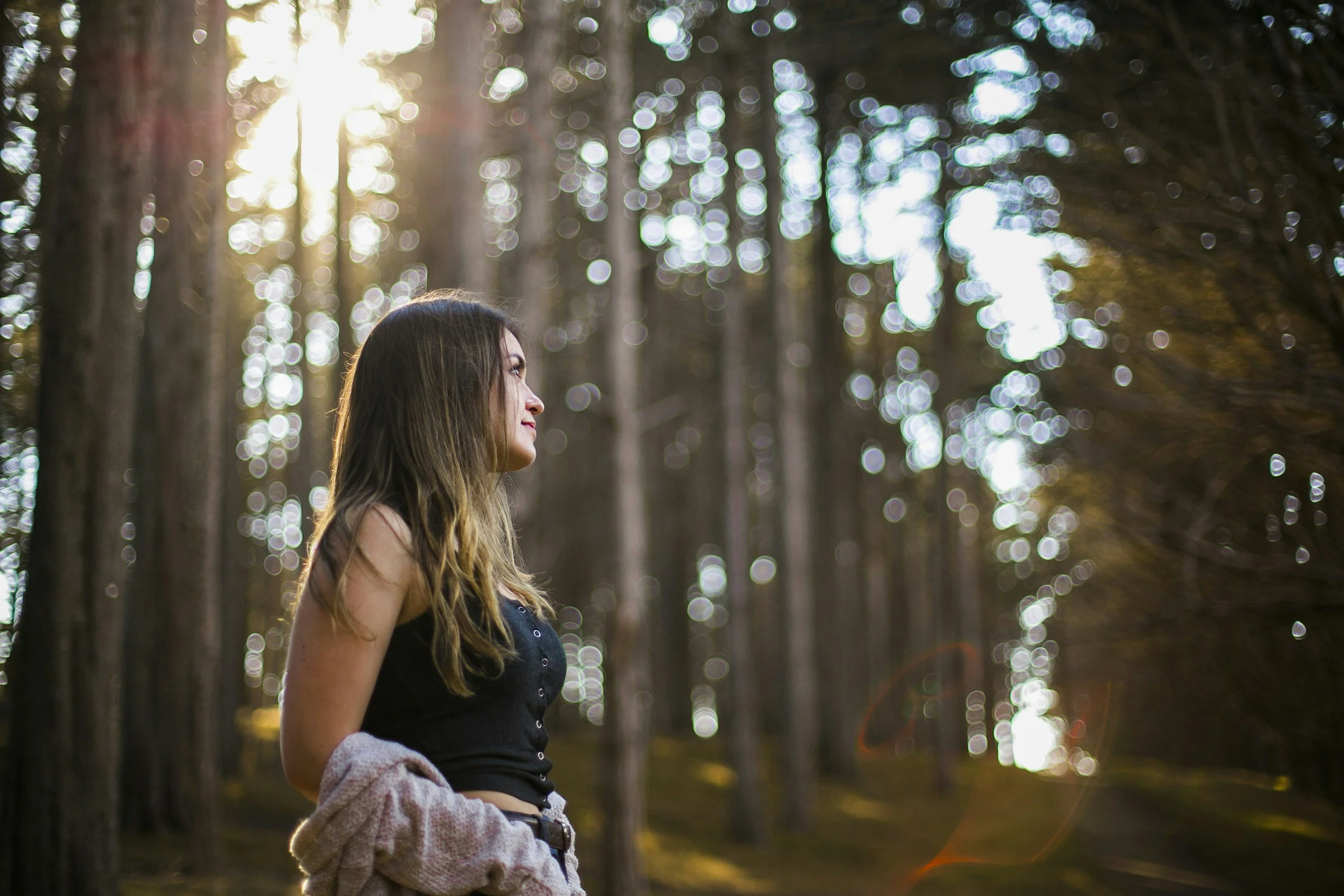 woman standing in a sunlit forest