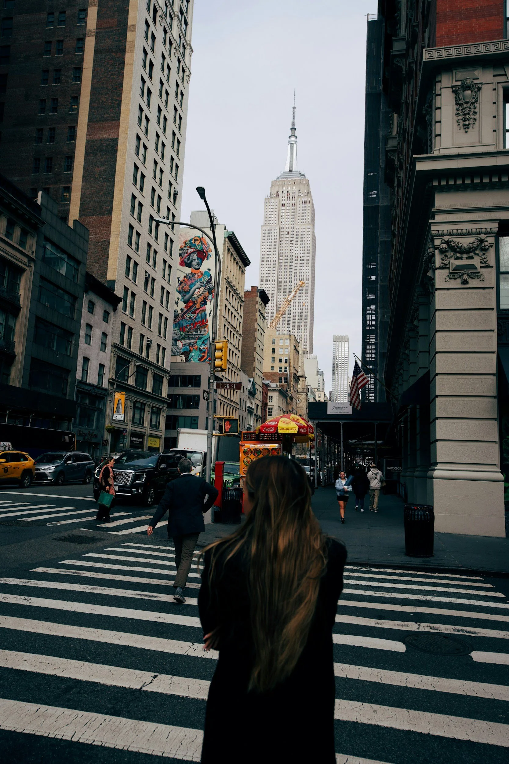 woman facing away from camera walking In New York City crosswalk