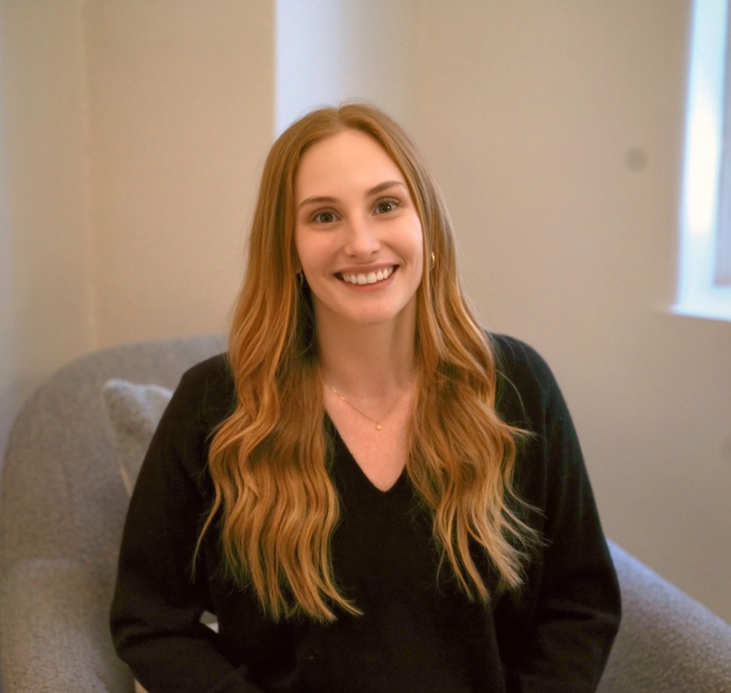 Woman with red hair smiling and sitting in therapist chair