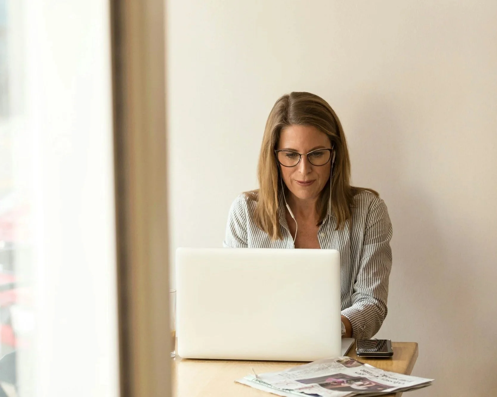 blonde woman siting at a computer with headphones in