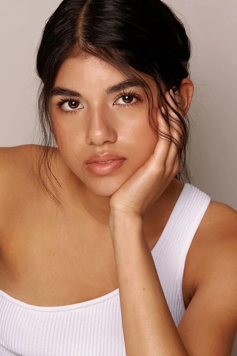 young model in white off-shoulder tank top leaning on elbow looking into the camera bored in a vancouver photo studio 