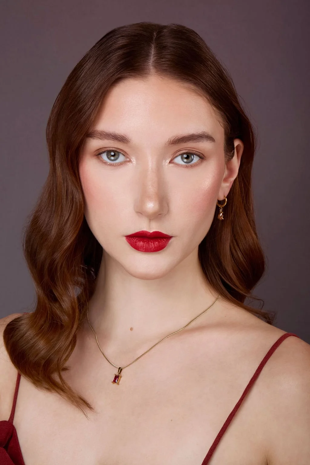 studio beauty portrait of red hair model with gold gemstone jewelry set and red lip