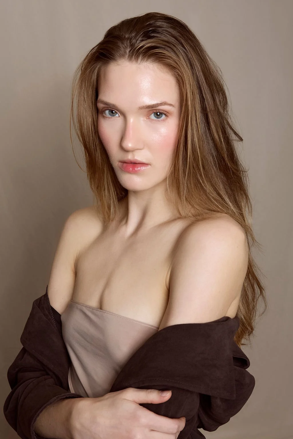 blond woman with tube top and brown jacket flirting with the camera in studio portrait by finegraphy photography