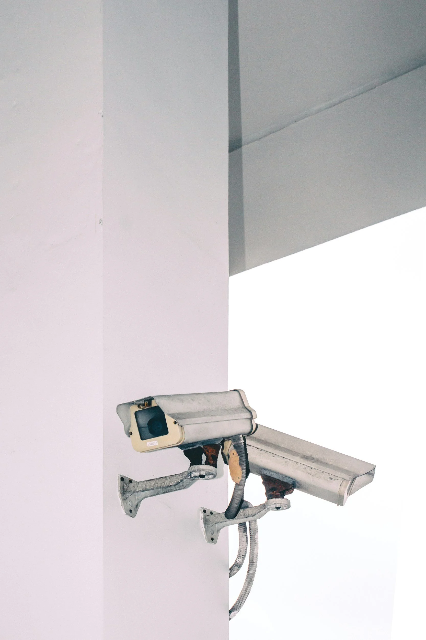 A security camera mounted on a white wall in an unfinished or empty room.