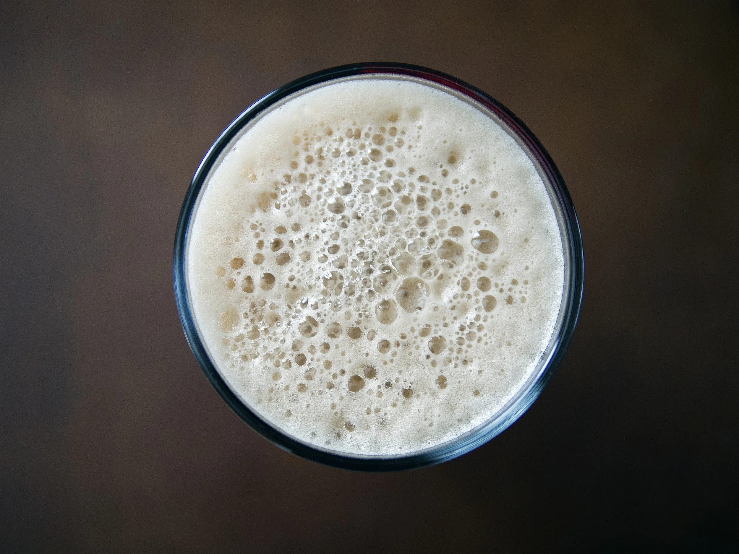 Top view of a glass filled with a frothy, creamy beverage, possibly a milkshake or smoothie.