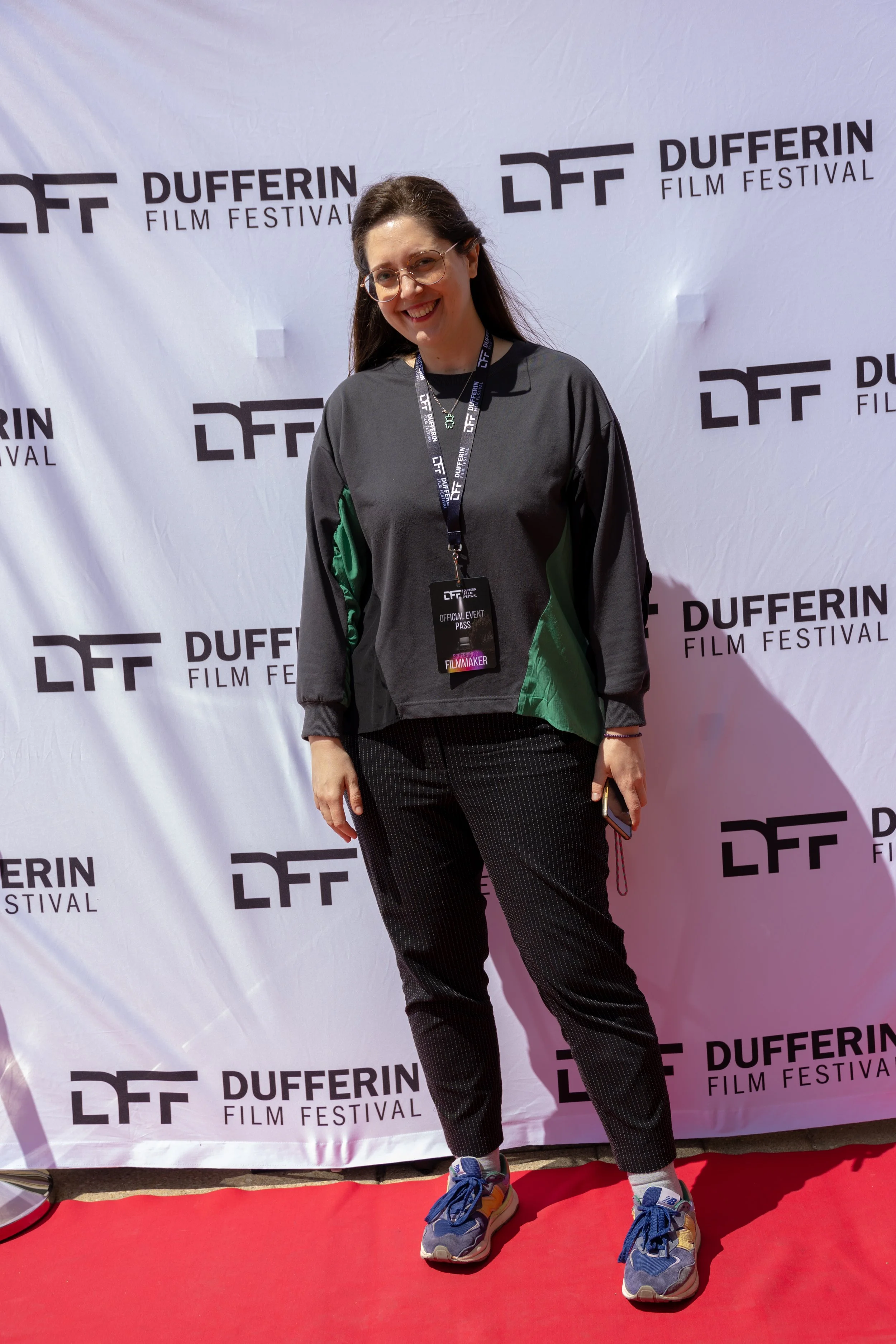 Person standing on red carpet at Dufferin Film Festival with event badge, wearing casual attire, smiling for the camera.