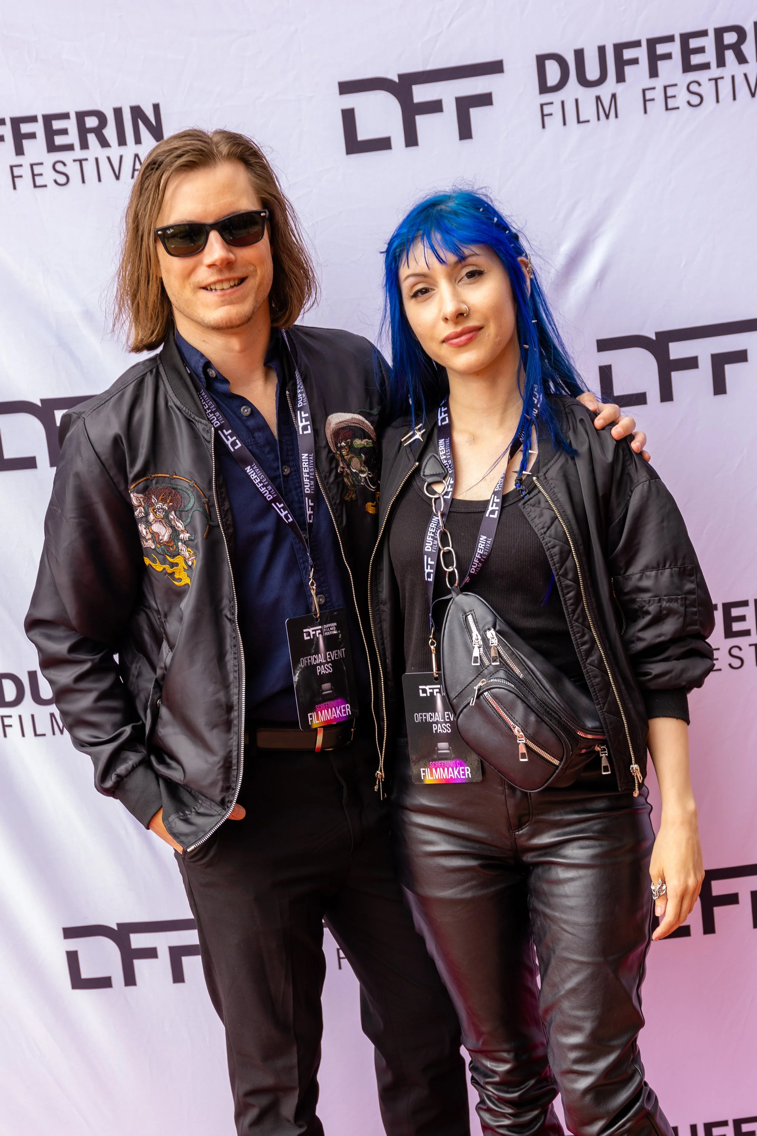 Two individuals at Dufferin Film Festival red carpet, wearing sunglasses and event passes