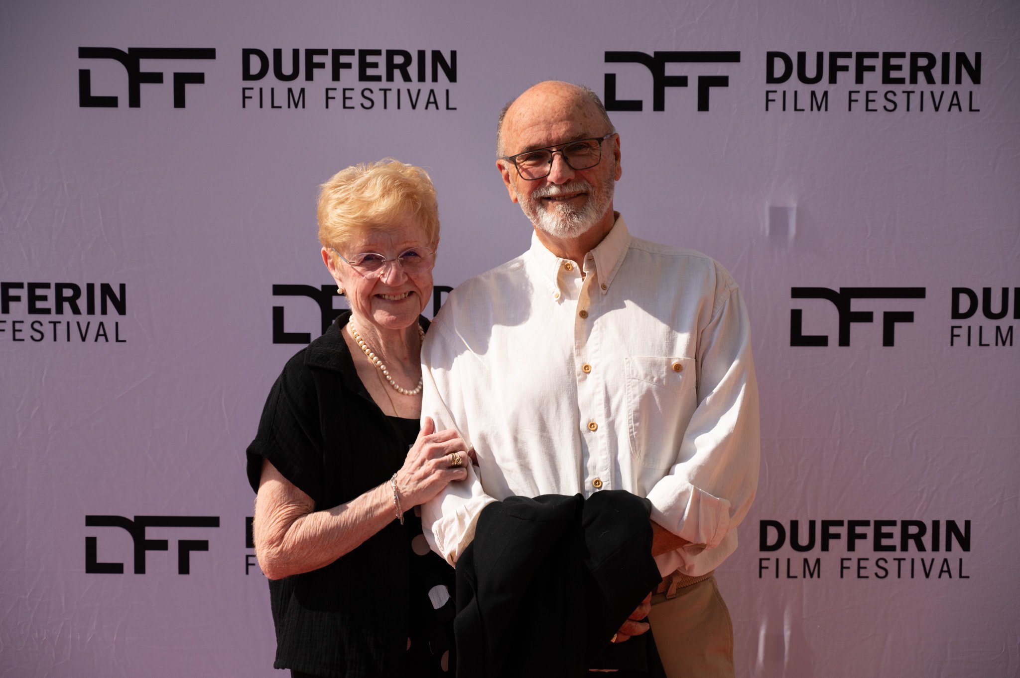 An elderly couple posing together on the red carpet at the Dufferin Film Festival.