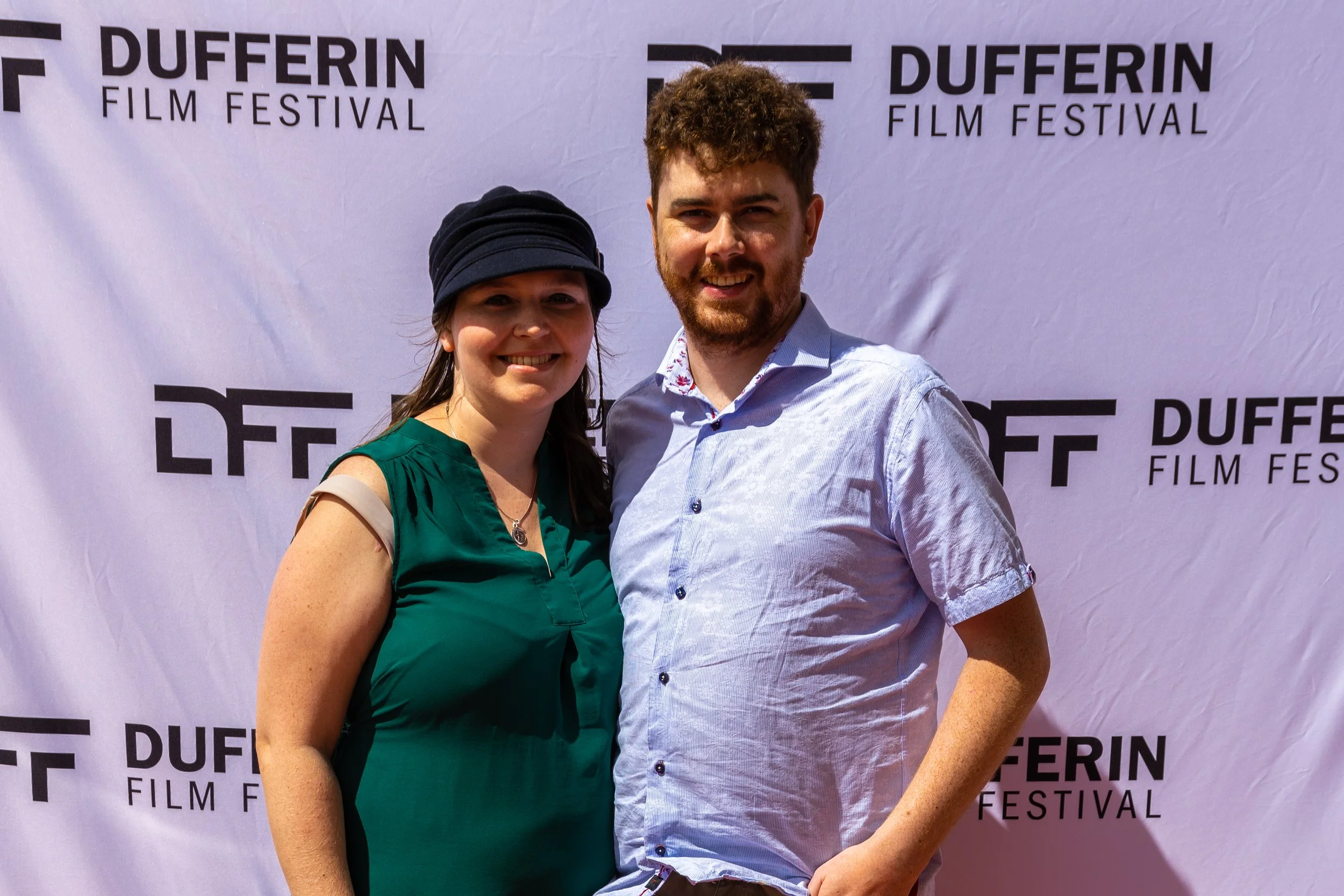 Two people smiling together in front of a Dufferin Film Festival backdrop.