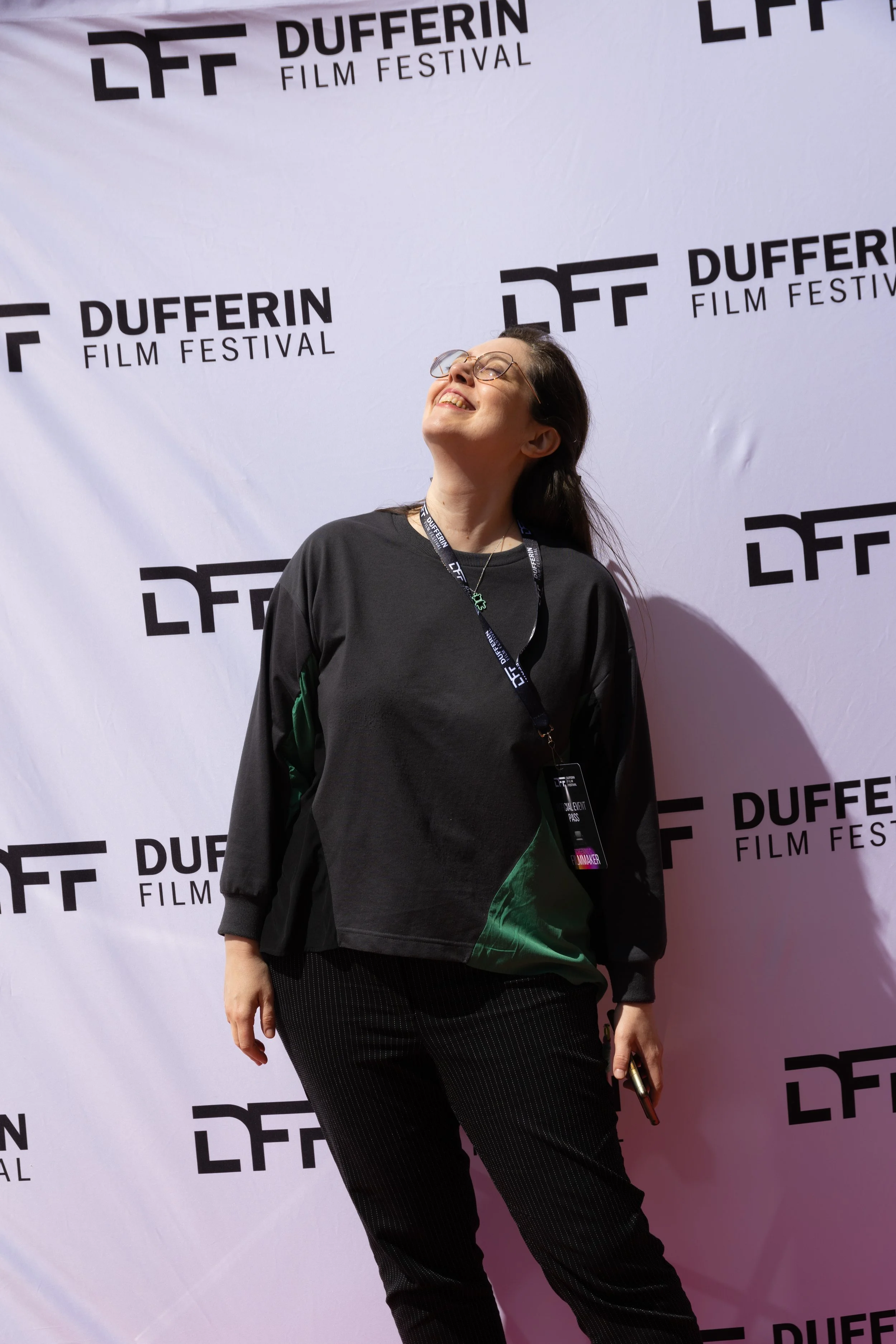 Person smiling and looking up at the Dufferin Film Festival, standing in front of a branded backdrop.