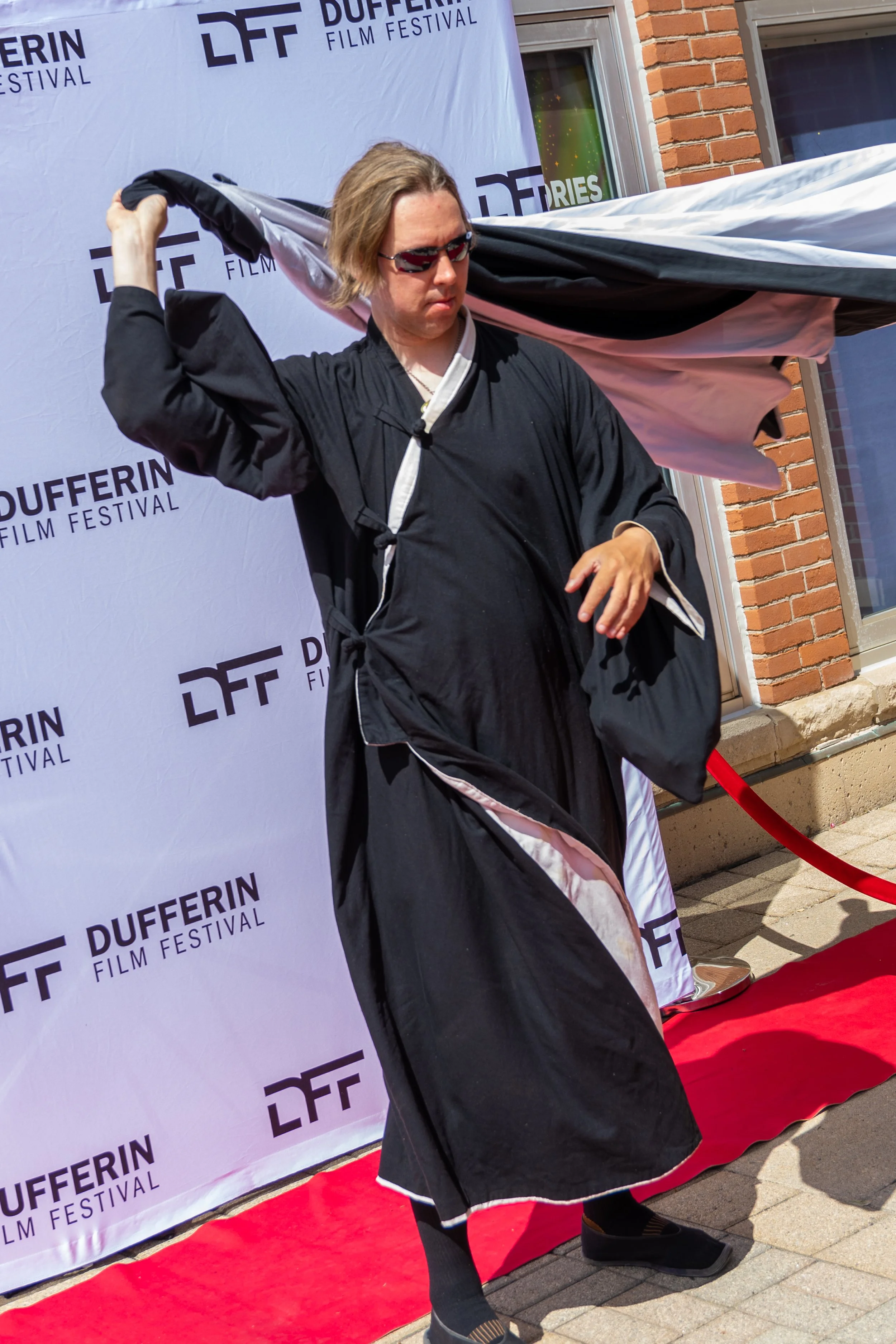 Person in black and white robe with sunglasses on red carpet at Dufferin Film Festival