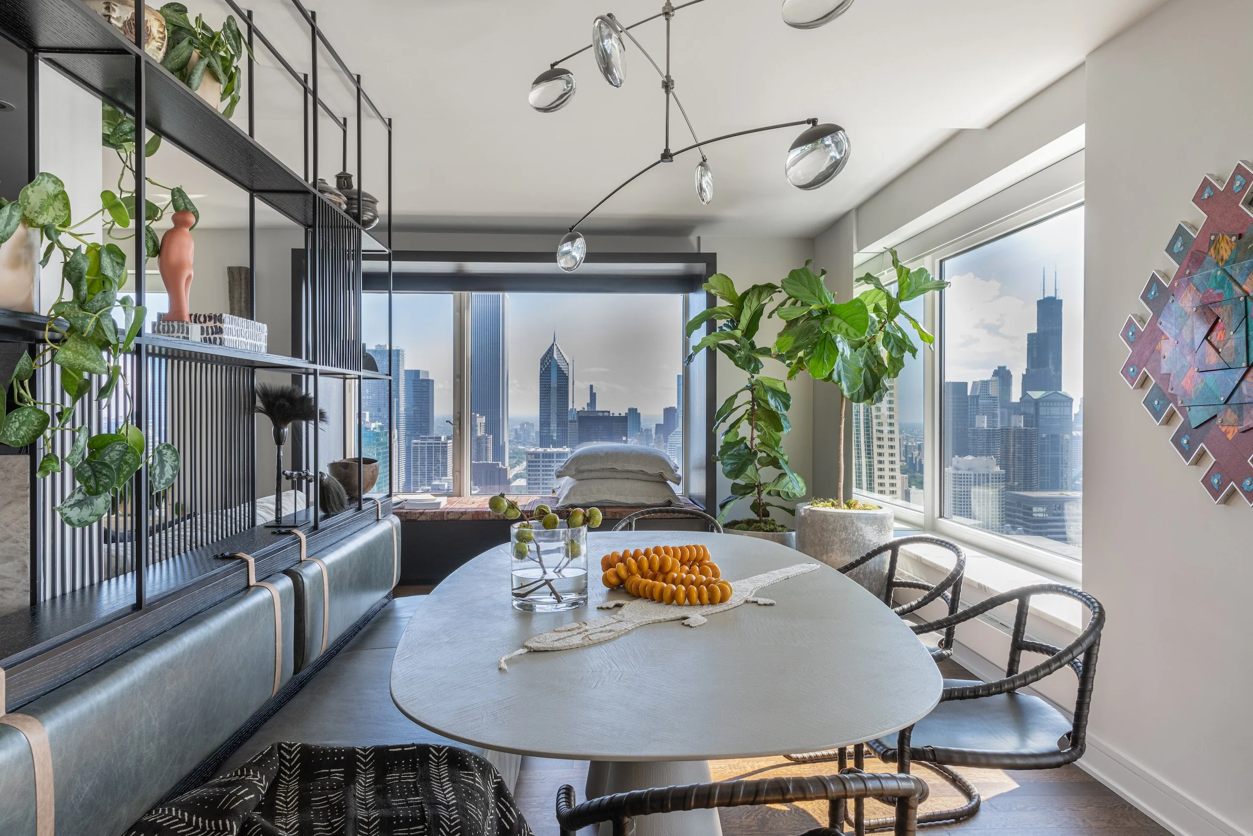 white oval organic oval dining table with leather bench in front of black open shelves and window bench behind it, Collector's Edition by PROjECT. interiors