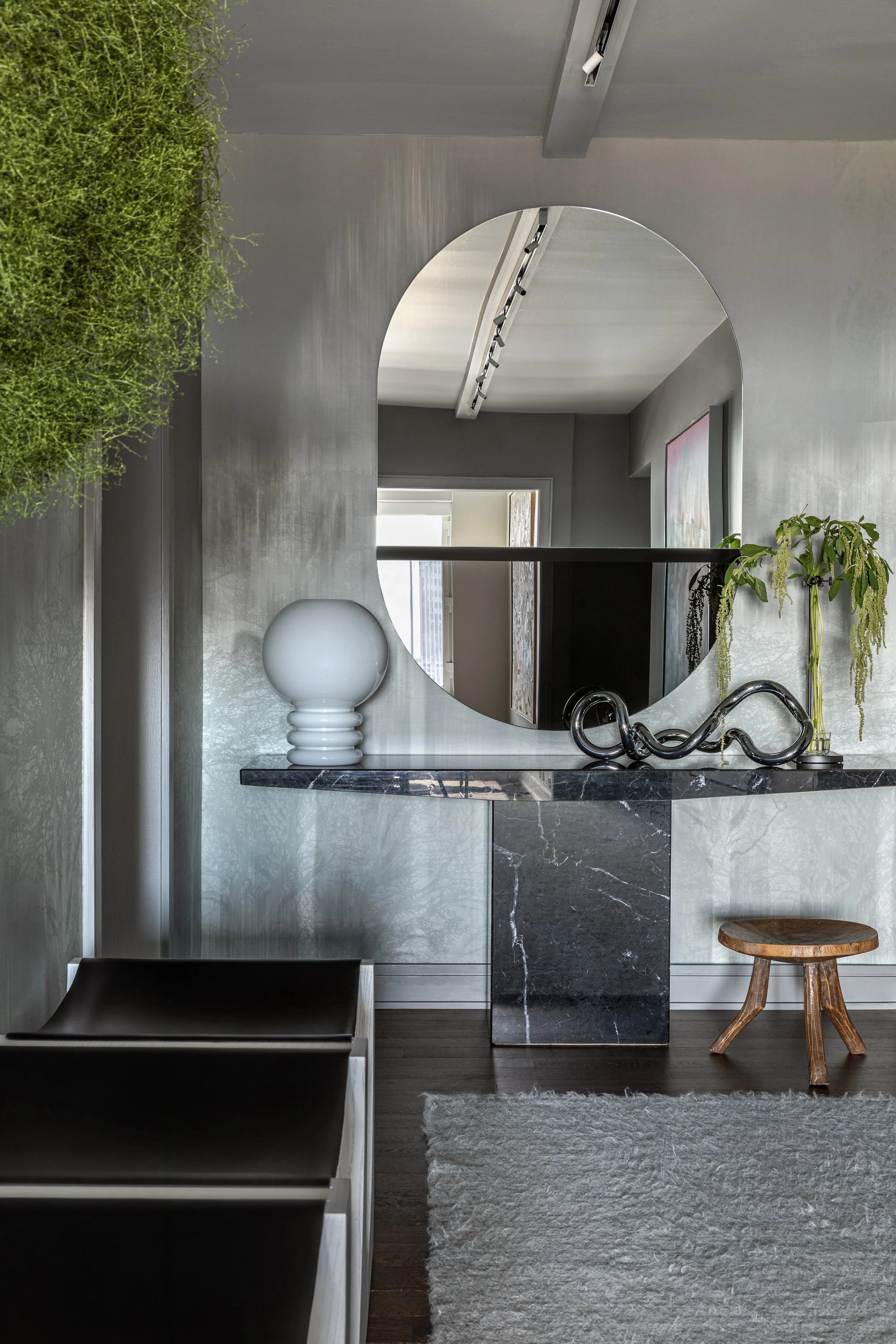 silver wallpaper walls and black marble table with large oval mirror above, Collector's Edition by PROjECT. interiors