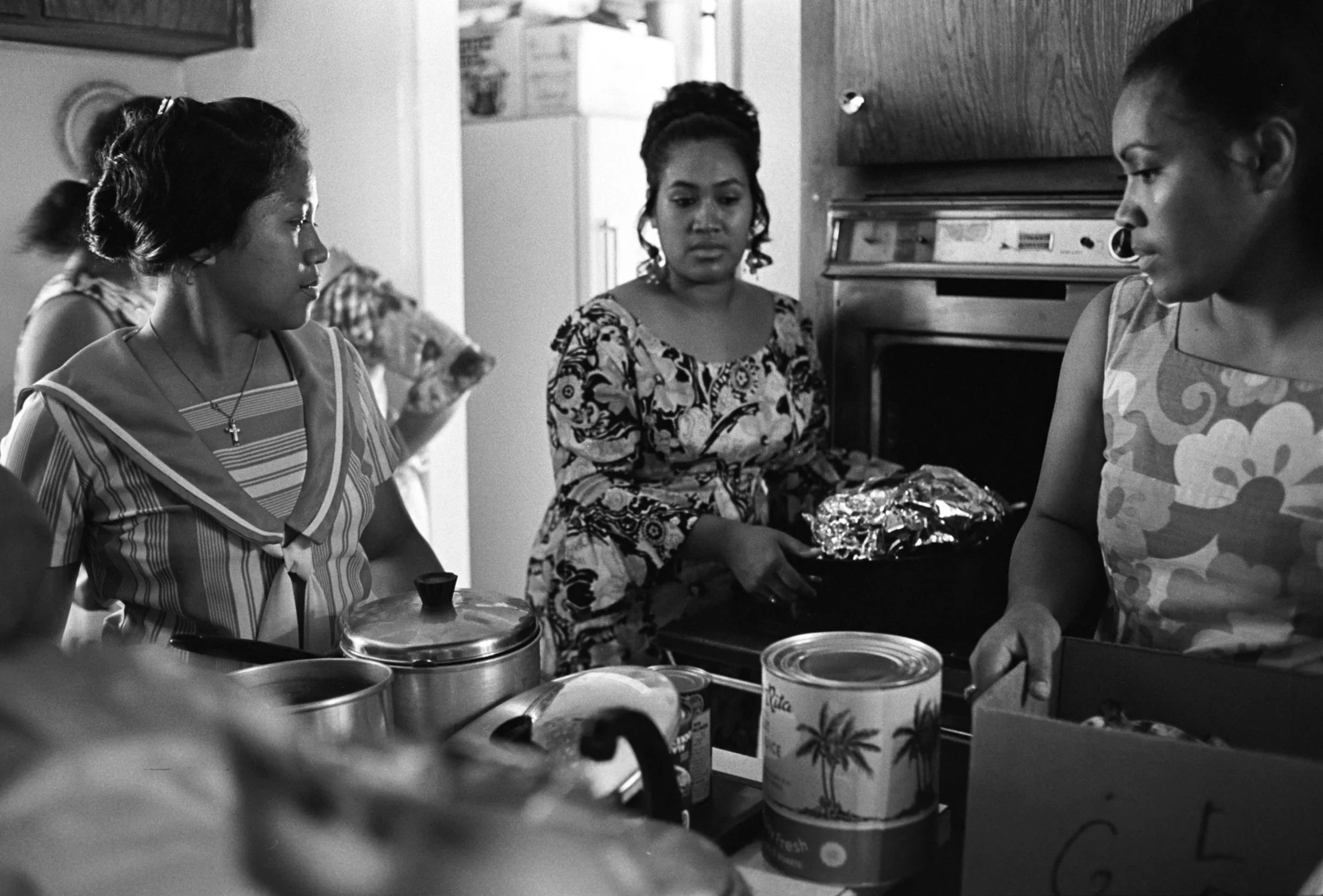People Cooking in Kitchen (1972),
People cooking in the kitchen. One person takes something wrapped in foil out of the oven.
Photographed by Alan Ohashi
