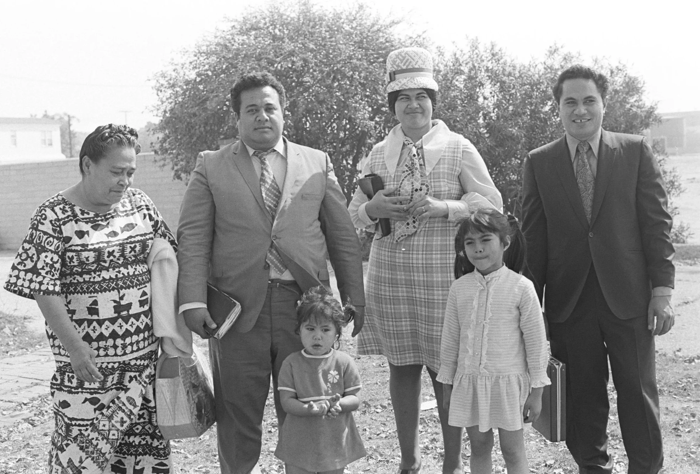 Members of Congregation (1972), 
(Samoan Church Service) Two men, two women, and two children of the congregation posing for the camera. 
Photographed by Alan Ohashi