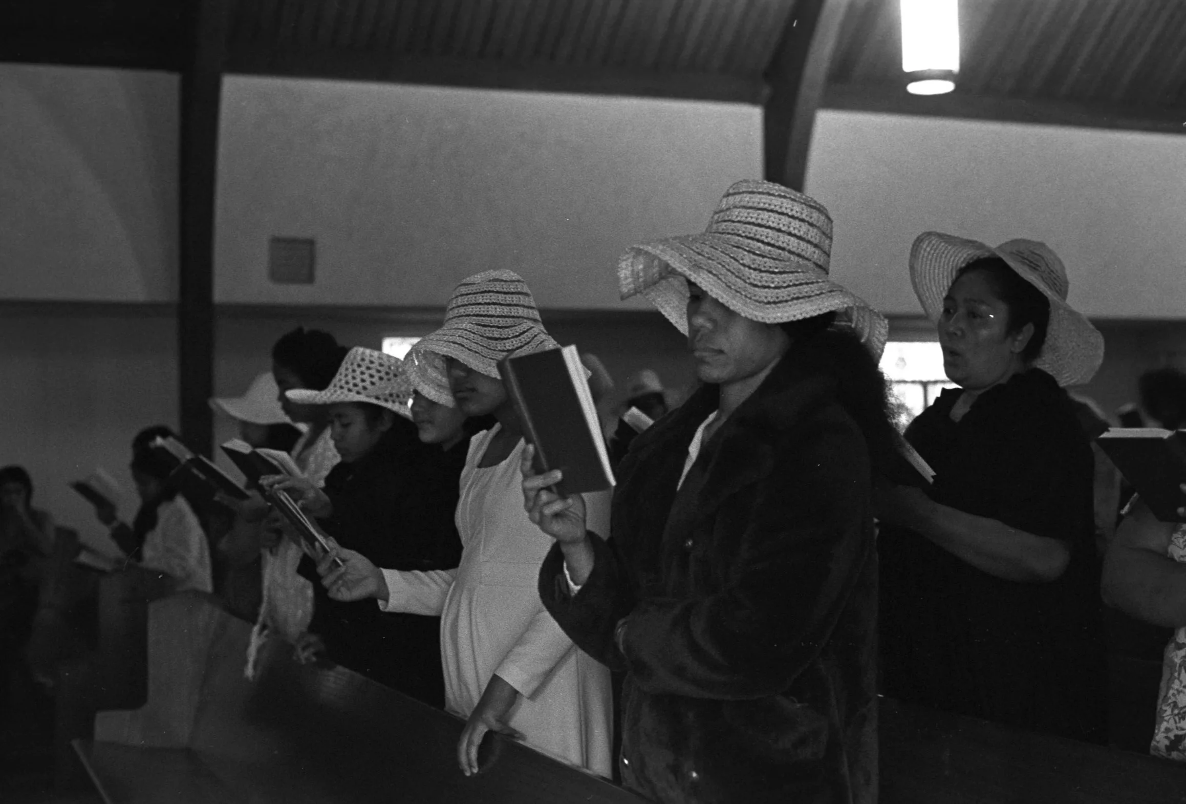 Church Service and Cookout (1972),
Church members standing at the front of the service reading books. church members standing at the front of the service reading books. 
Photographed by Visual Communications