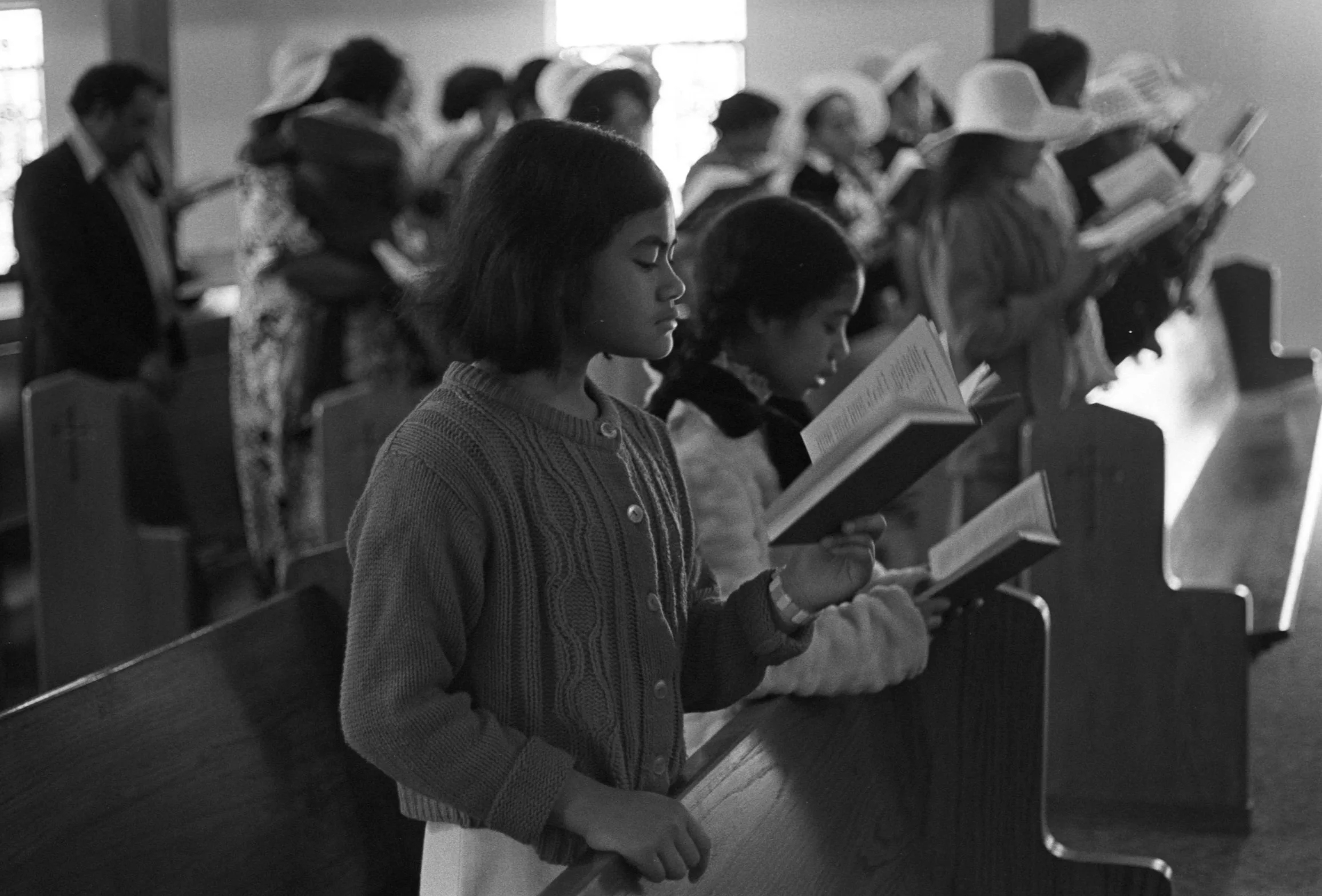 Church Service and Cookout (1972),
A close up of two children reading along with the church service.
Photographed by Visual Communications
