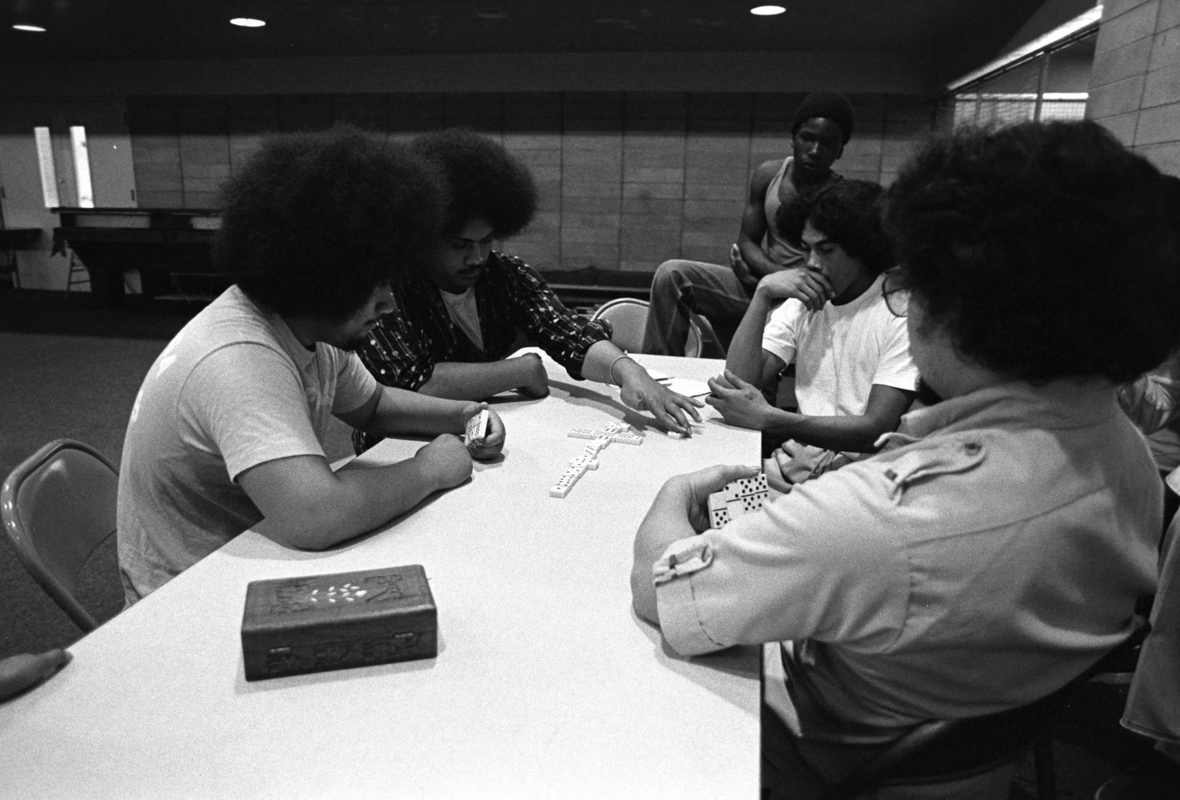 Omai Fa'atasi - Basketball in Carson (1977-1978),
A group seated playing dominos.
Photographed by Visual Communications