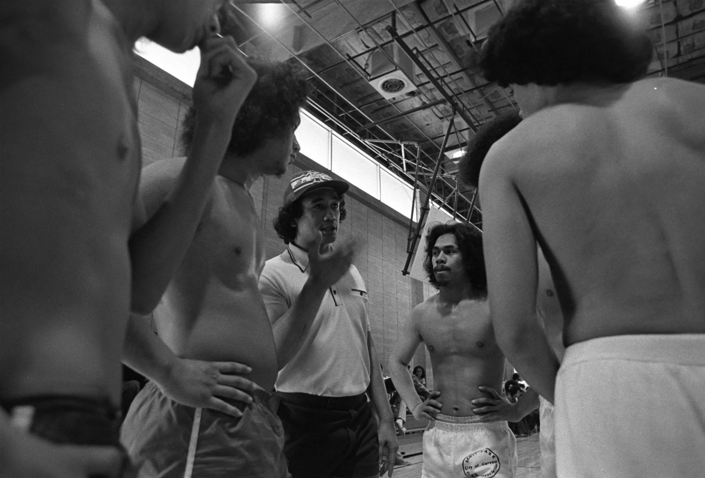 Basketball Players and Coach (1977-1978),
The coach speaks to his team that has gathered in a circle.
Photographed by Visual Communications