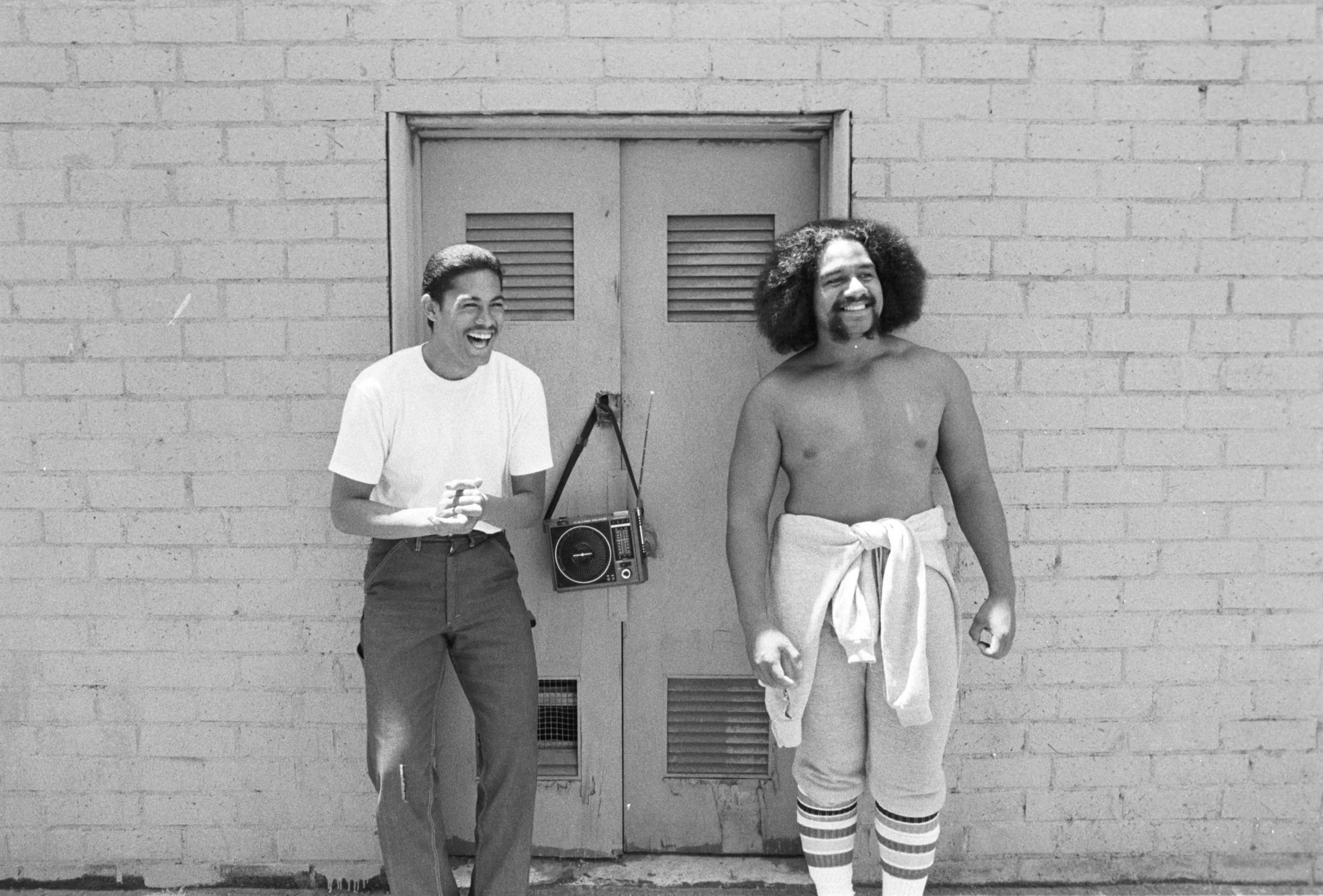 People Laughing with Stereo Outside Omai Office (1977-1978),
Two people with their stereo outside the Omai Headquarters in Carson.
Photographed by Visual Communications