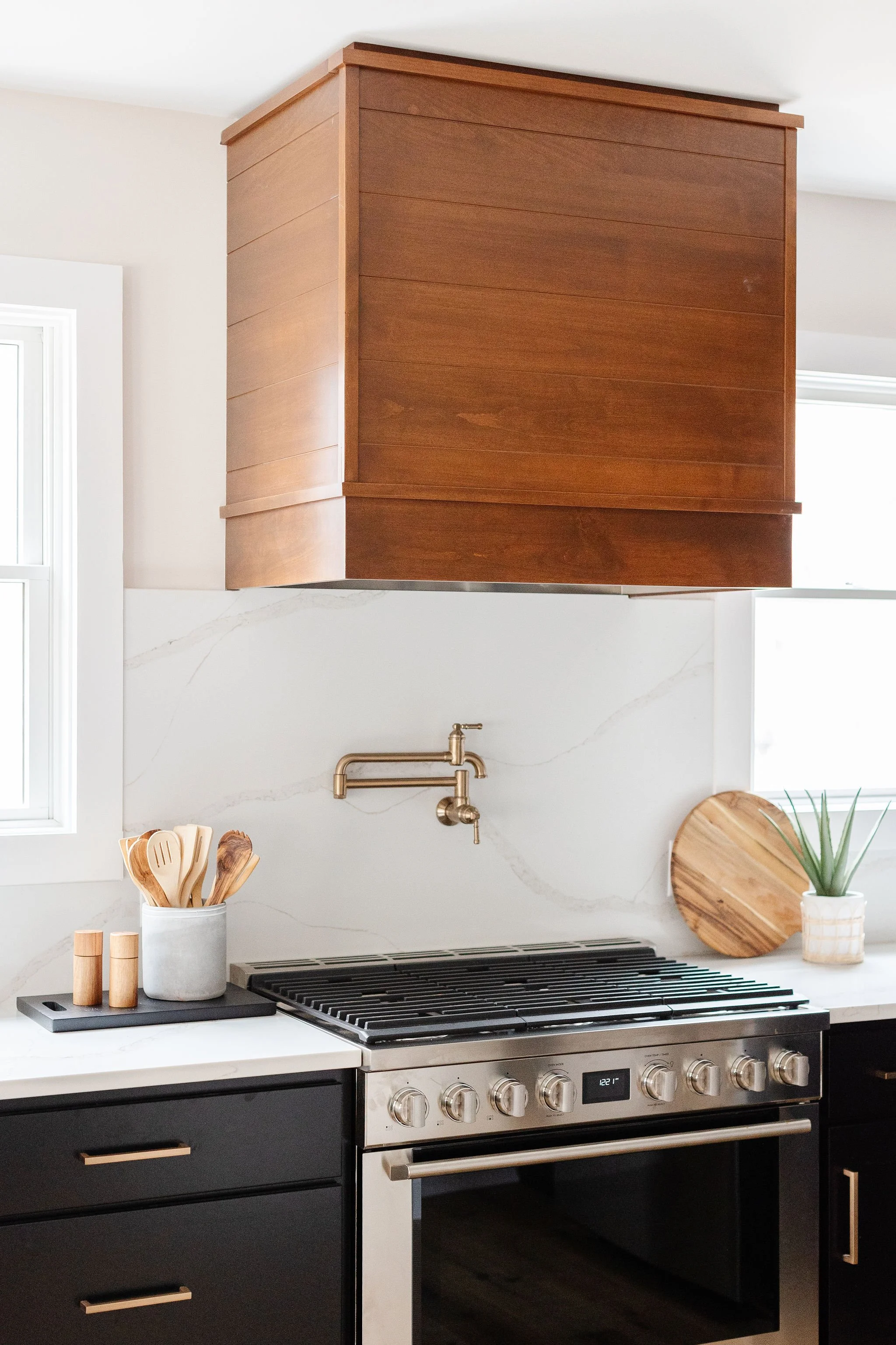 wood range hood and white stone backsplash