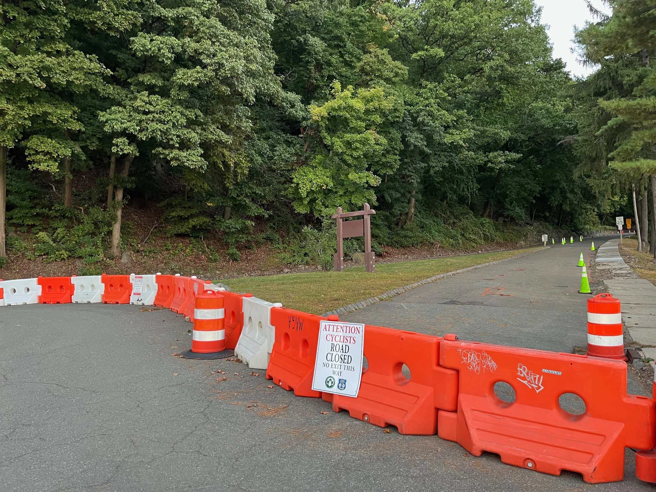 A photo of Henry Hudson Drive in the NJ Palisades with orange and white road blocks and a sign that reads: Attention Cyclists Road Closed.