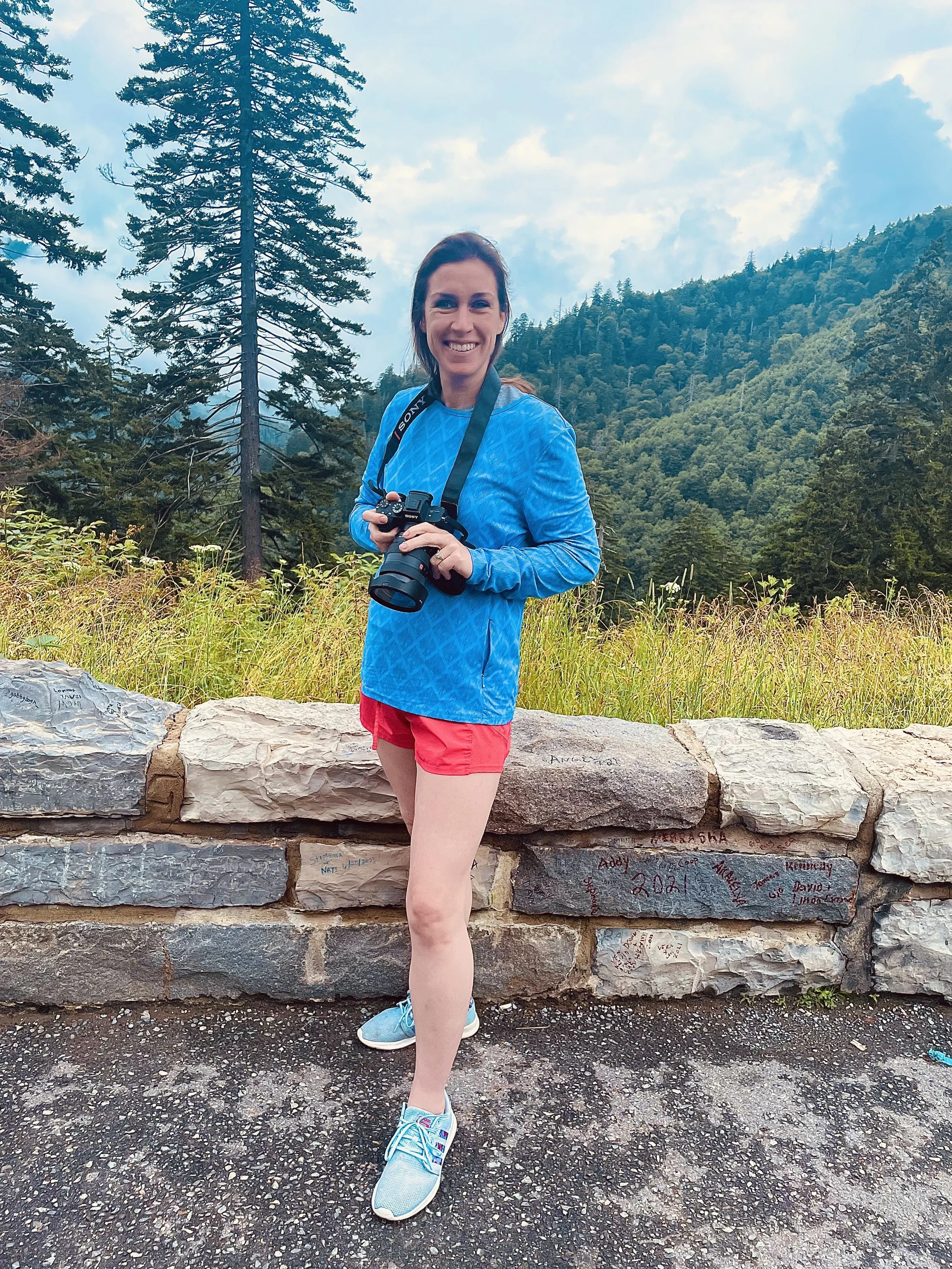 A woman standing in front of a large green Hulk statue, mimicking its aggressive pose with her mouth open in surprise or excitement.