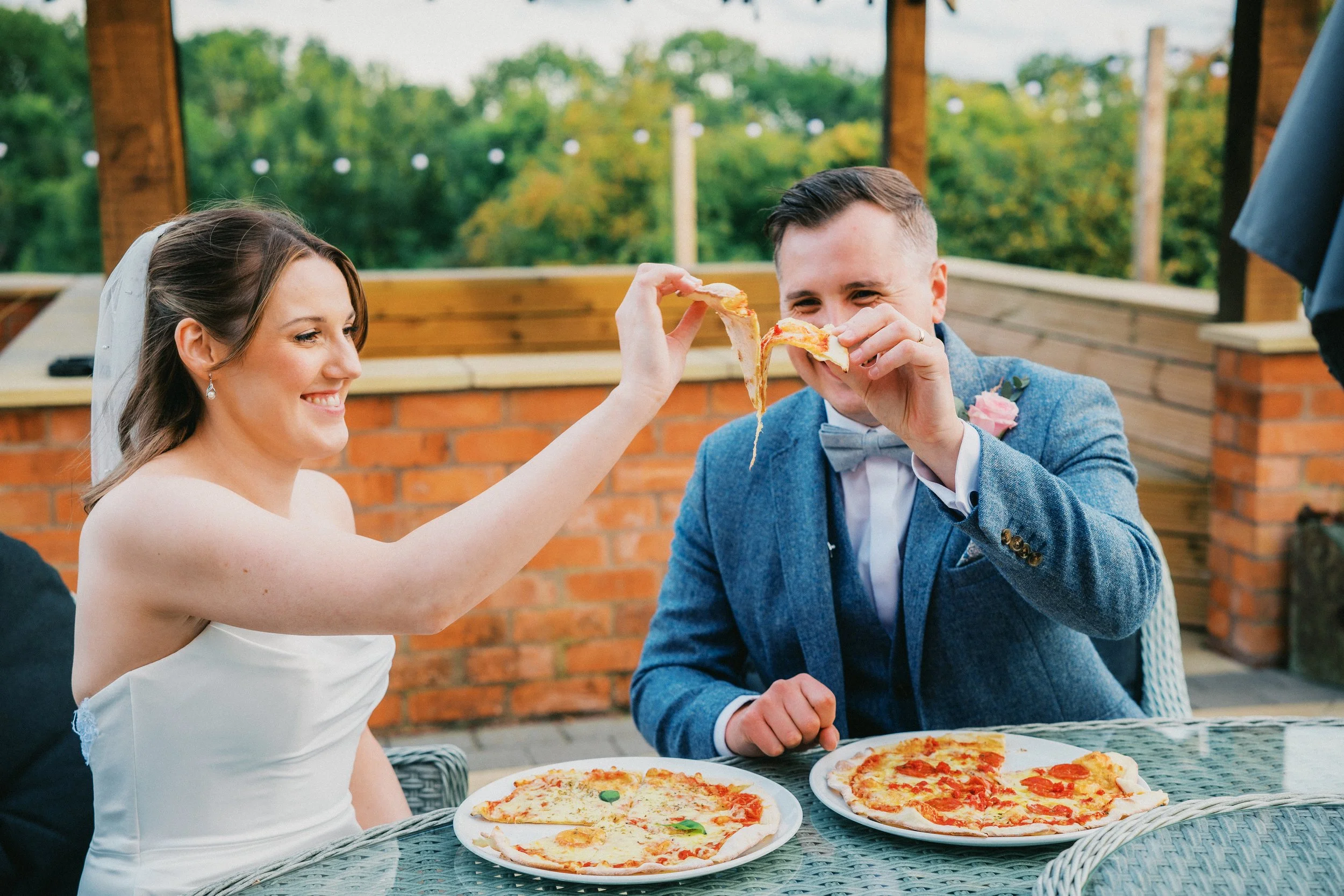 Bride and groom cheering their slices of pizza together