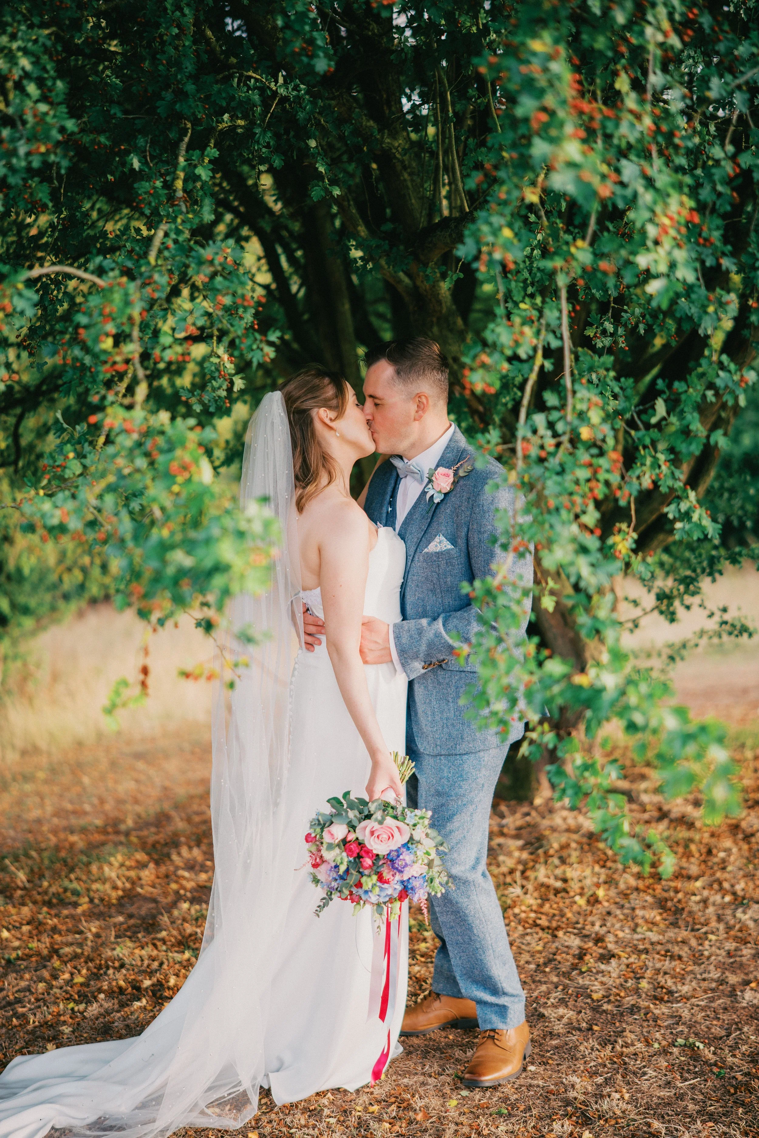 Bride and Groom Kissing surrounded by green leaves