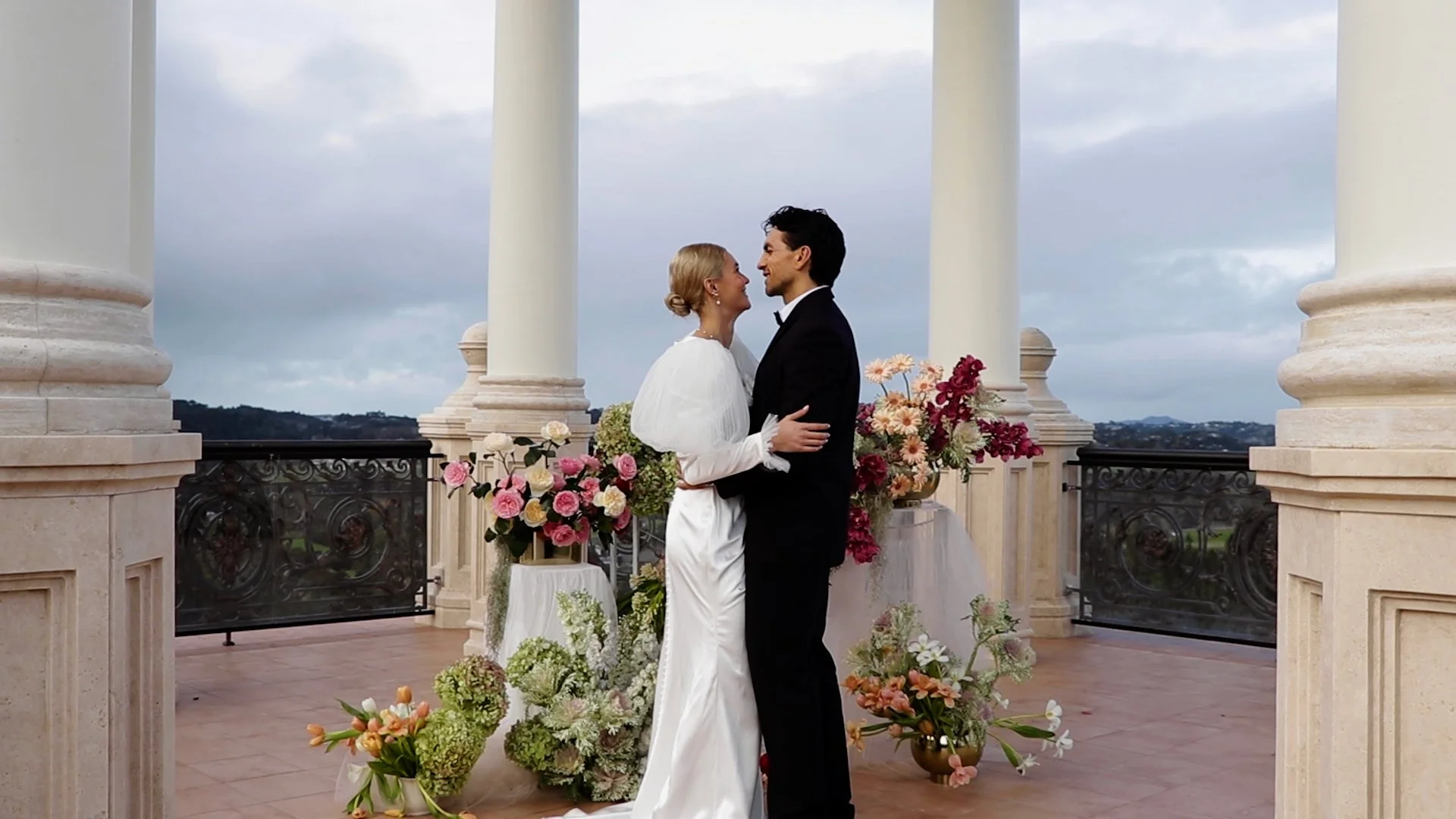 A bride and groom embracing on a terrace at Lone Pine Estate, Auckland - a beautiful marriage ceremony location.