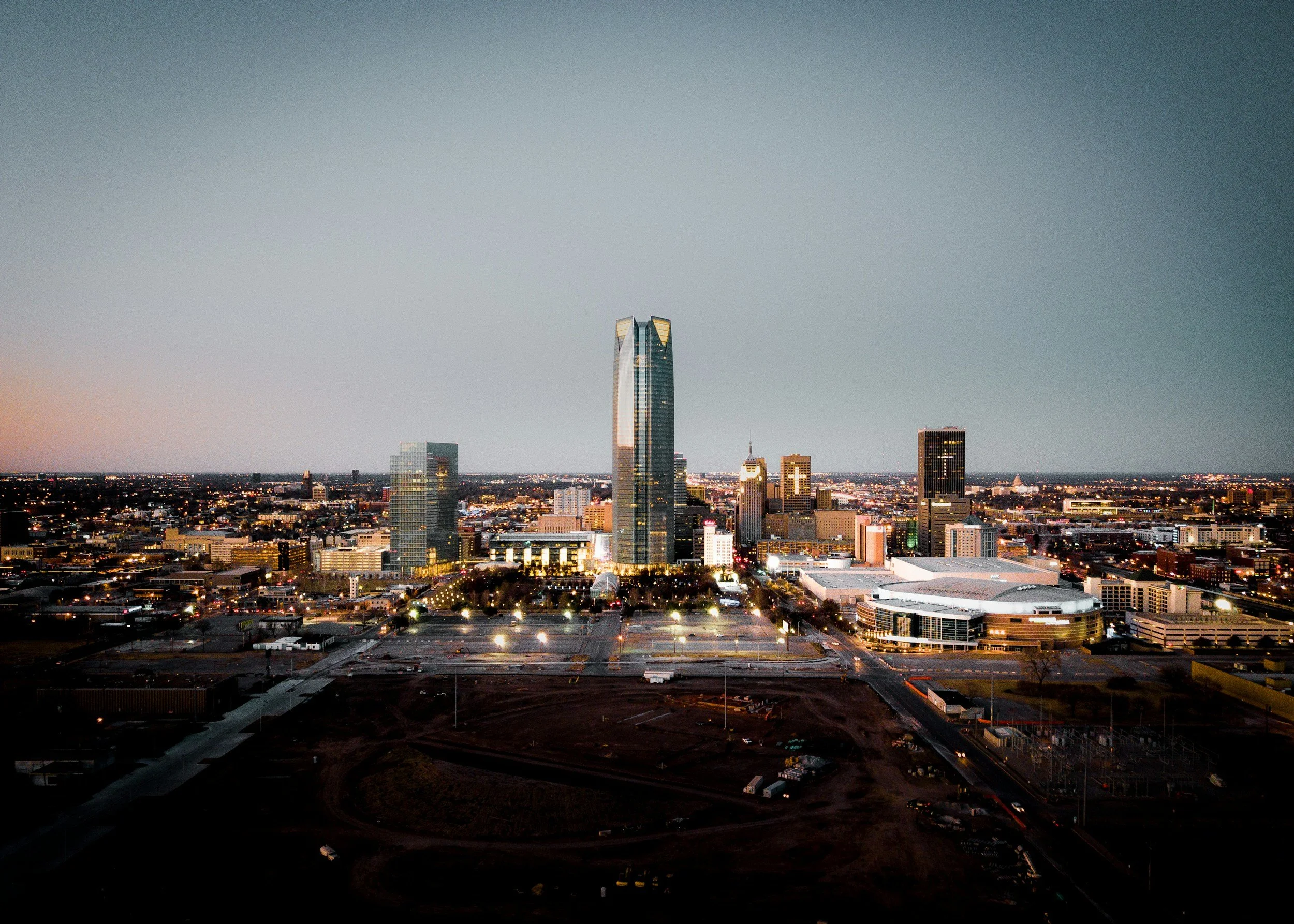 A city skyline at dusk with tall modern buildings and a clear sky.