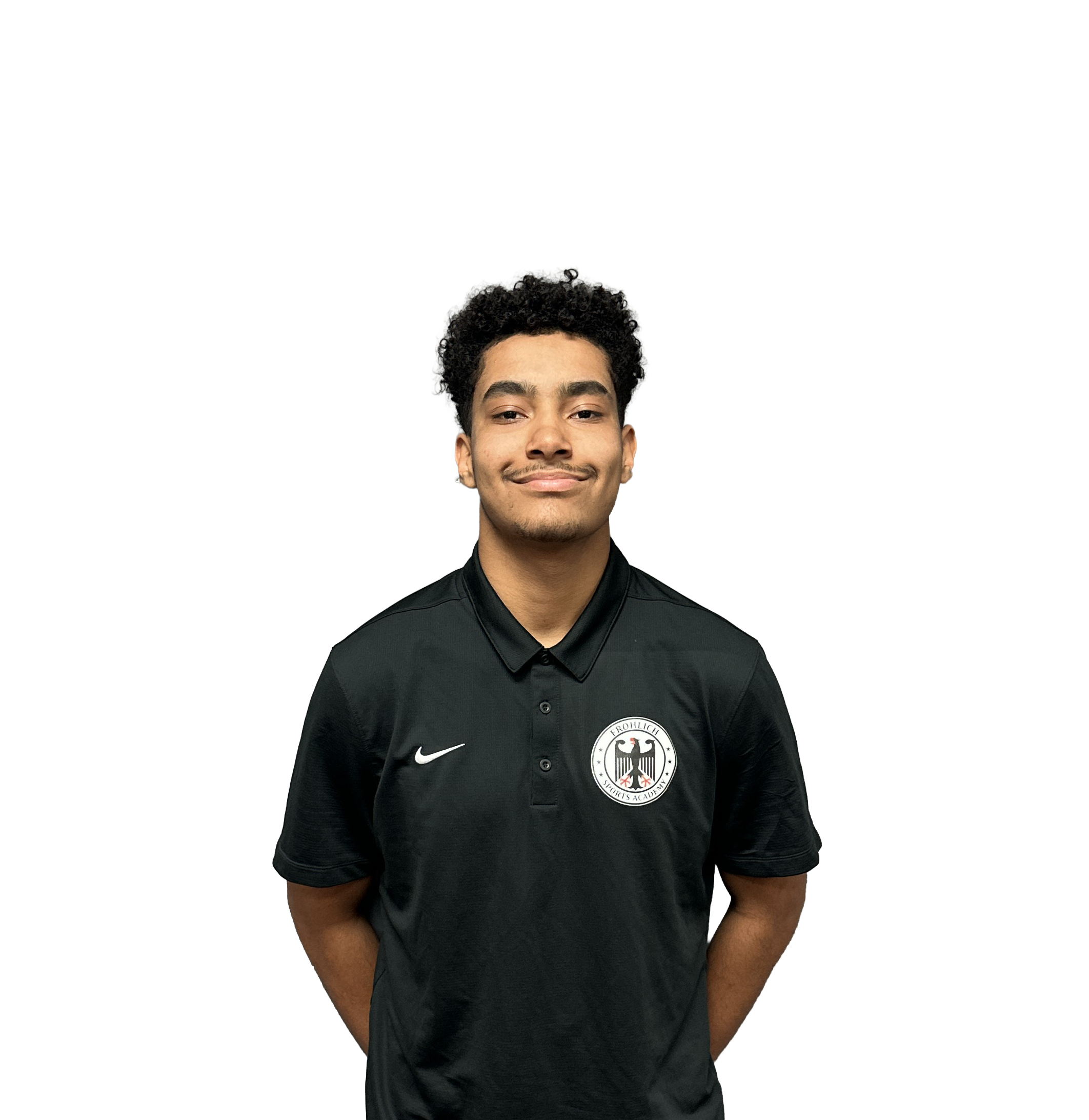 Young man with curly hair wearing a black Nike polo shirt with a sports academy emblem